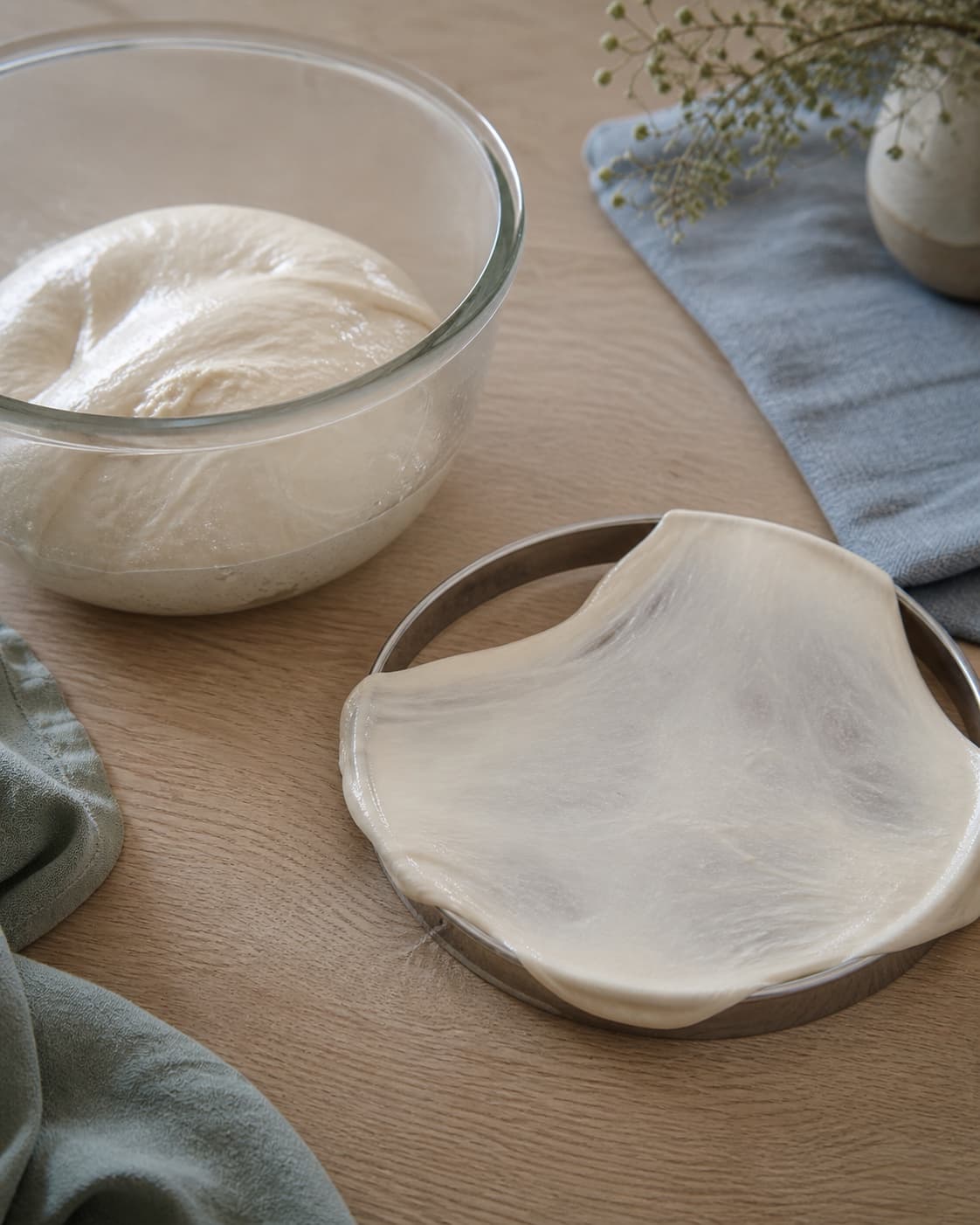 blank elastisk pizzadej i skål med en tynd strakt glutenvindueprøve og ingen løst mel; kontroltegnet er dejen er glat, elastisk og danner en næsten gennemsigtig rude mellem fingrene