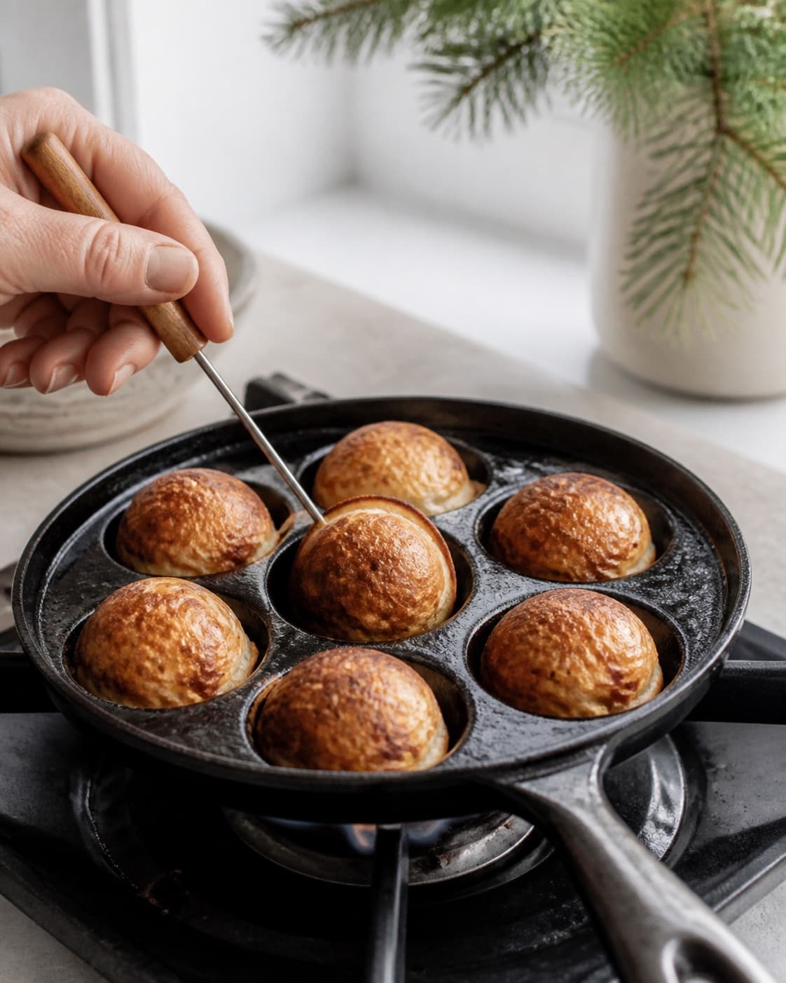 Danish aebleskiver being turned in stages to form round evenly golden balls under tilberedningen af æbleskiver
