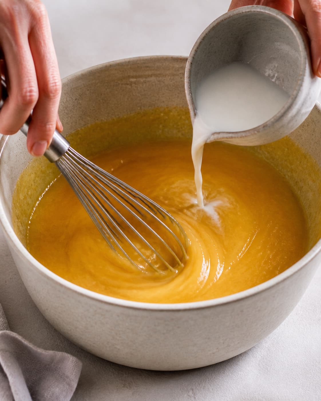 Cornstarch slurry being whisked into glossy orange sauce before fresh zest is added under tilberedningen af appelsinsauce og karameliserede mandler til risalamande