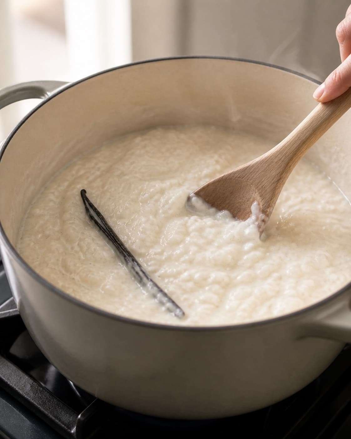 Creamy rice porridge with vanilla cooking slowly in a heavy saucepan under tilberedningen af risalamande