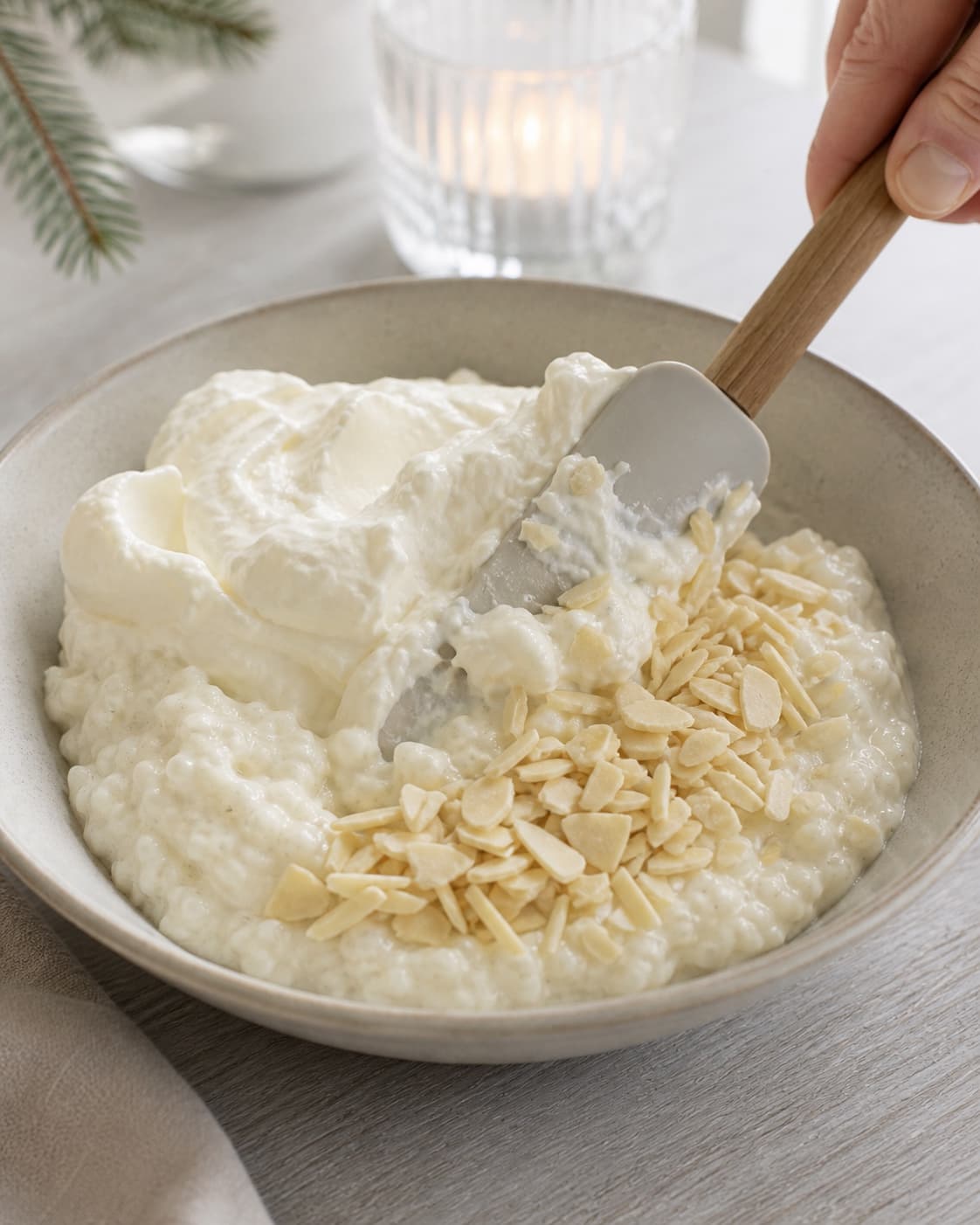 Chopped blanched almonds and softly whipped cream being folded into cold vanilla rice porridge under tilberedningen af risalamande