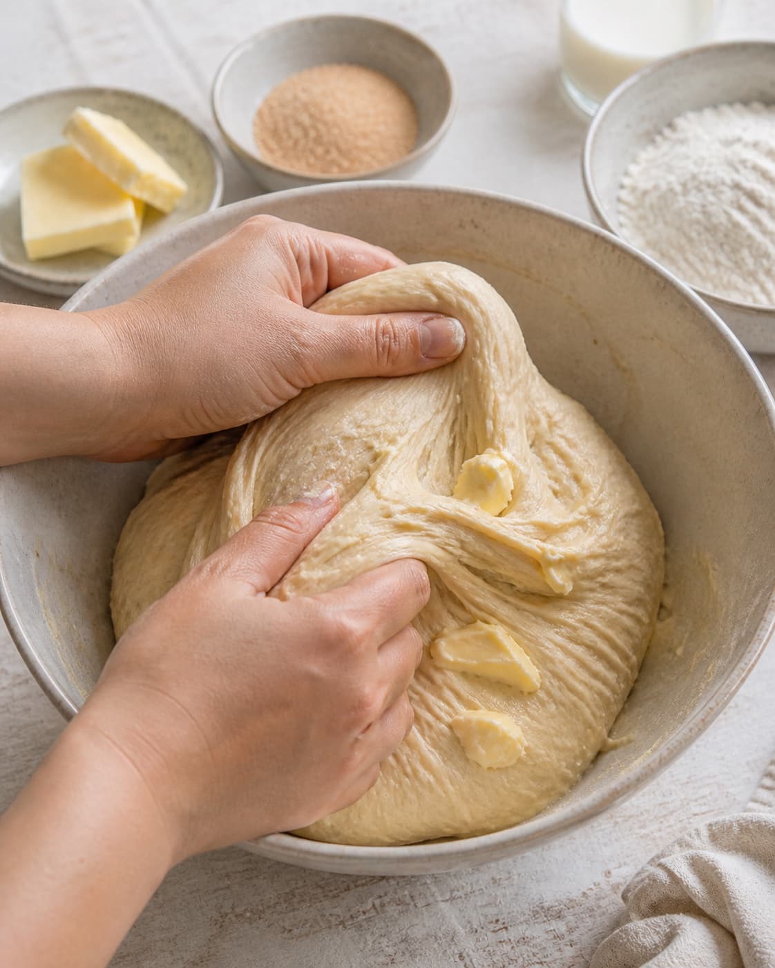Soft butter being kneaded gradually into elastic sweet bun dough under tilberedningen af kanelboller med chokolade