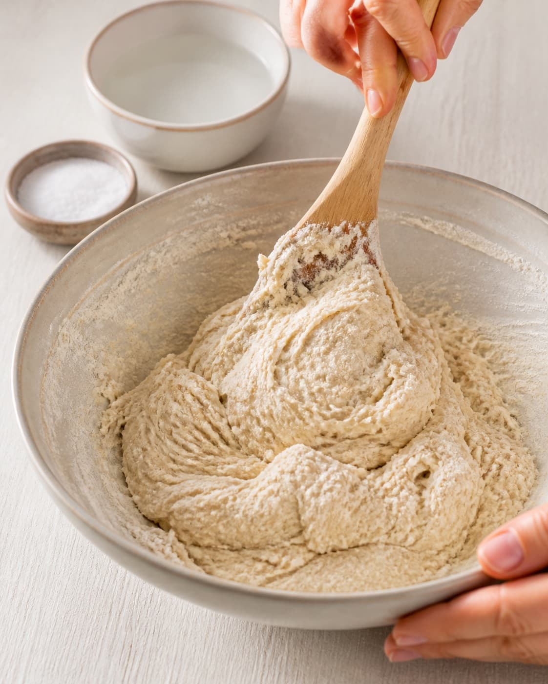 Flour warm water yeast and salt being mixed into a soft bread dough under tilberedningen af boller med tomat og bacon