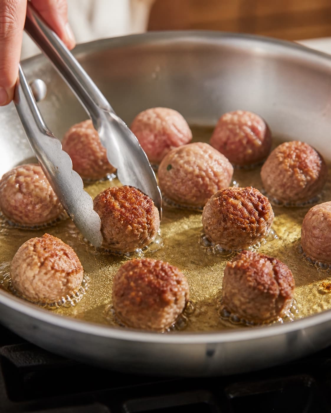 Small beef meatballs with breadcrumbs egg parmesan onion and garlic browning in olive oil under tilberedningen af spaghetti à la lady og vagabonden