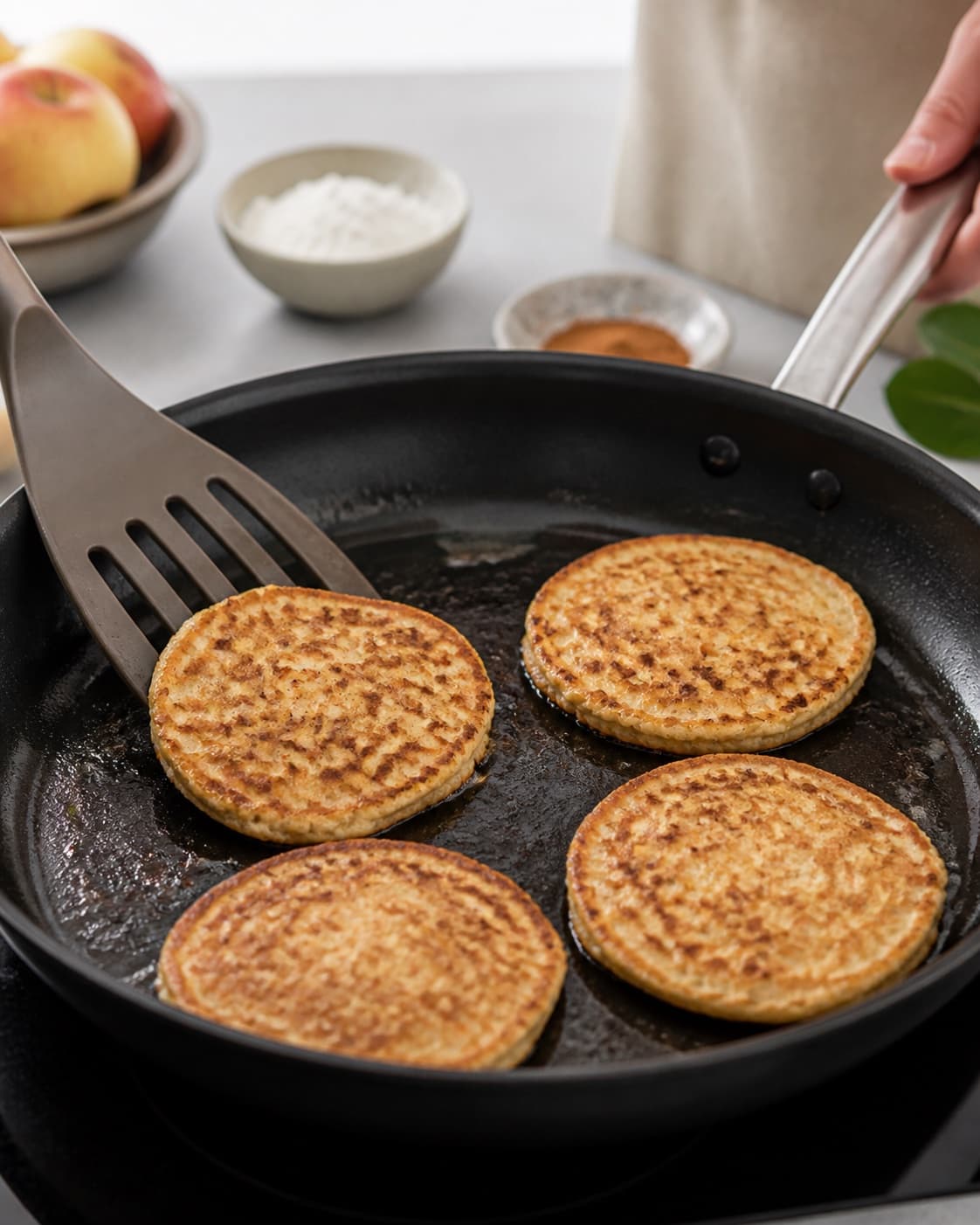 Apple cinnamon pancakes turning golden after bubbles set across their surfaces under tilberedningen af æblepandekager med kanel