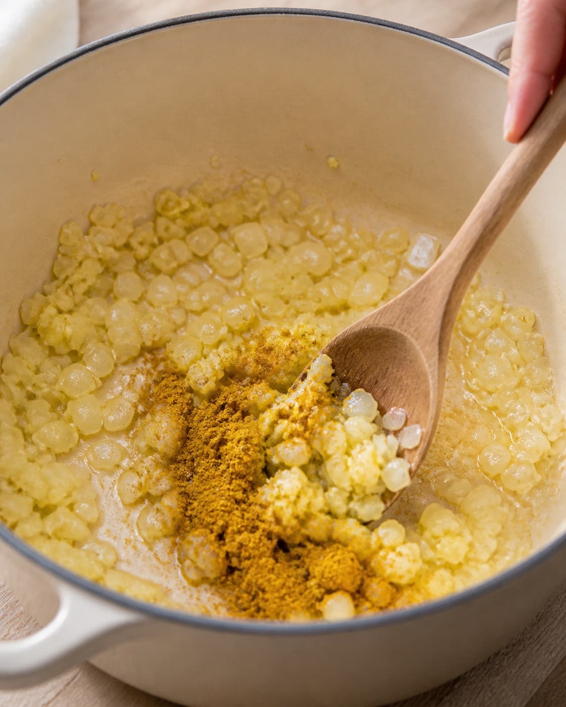 Onion garlic ginger and curry blooming gently in a wide pot under tilberedningen af rodfrugter i kokosmælk