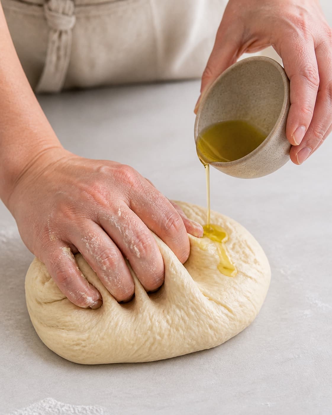 Olive oil being kneaded gradually into elastic pizza dough under tilberedningen af pizza med laks og wasabi