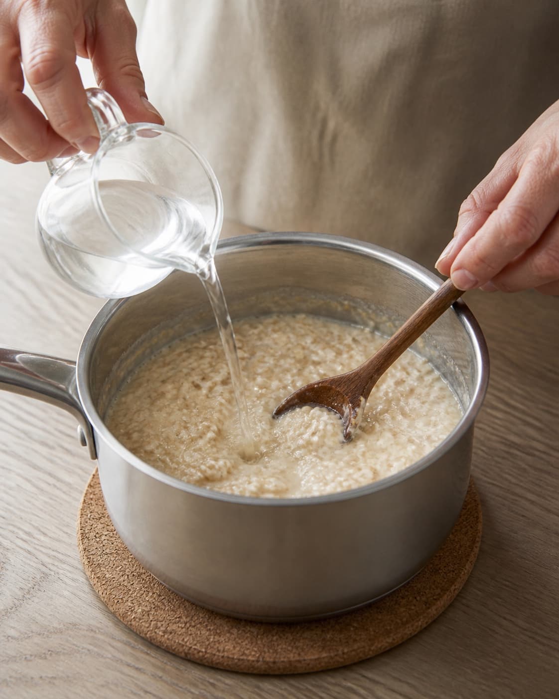 Creamy oat porridge being loosened with a little hot water off the heat under tilberedningen af havregrød