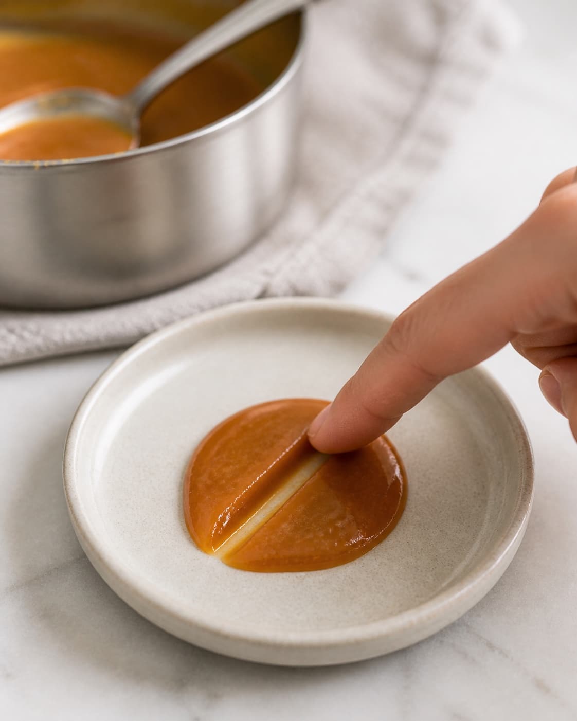 A chilled spoonful of caramel holding a soft line during a consistency test under tilberedningen af cremet karamel af kondenseret mælk
