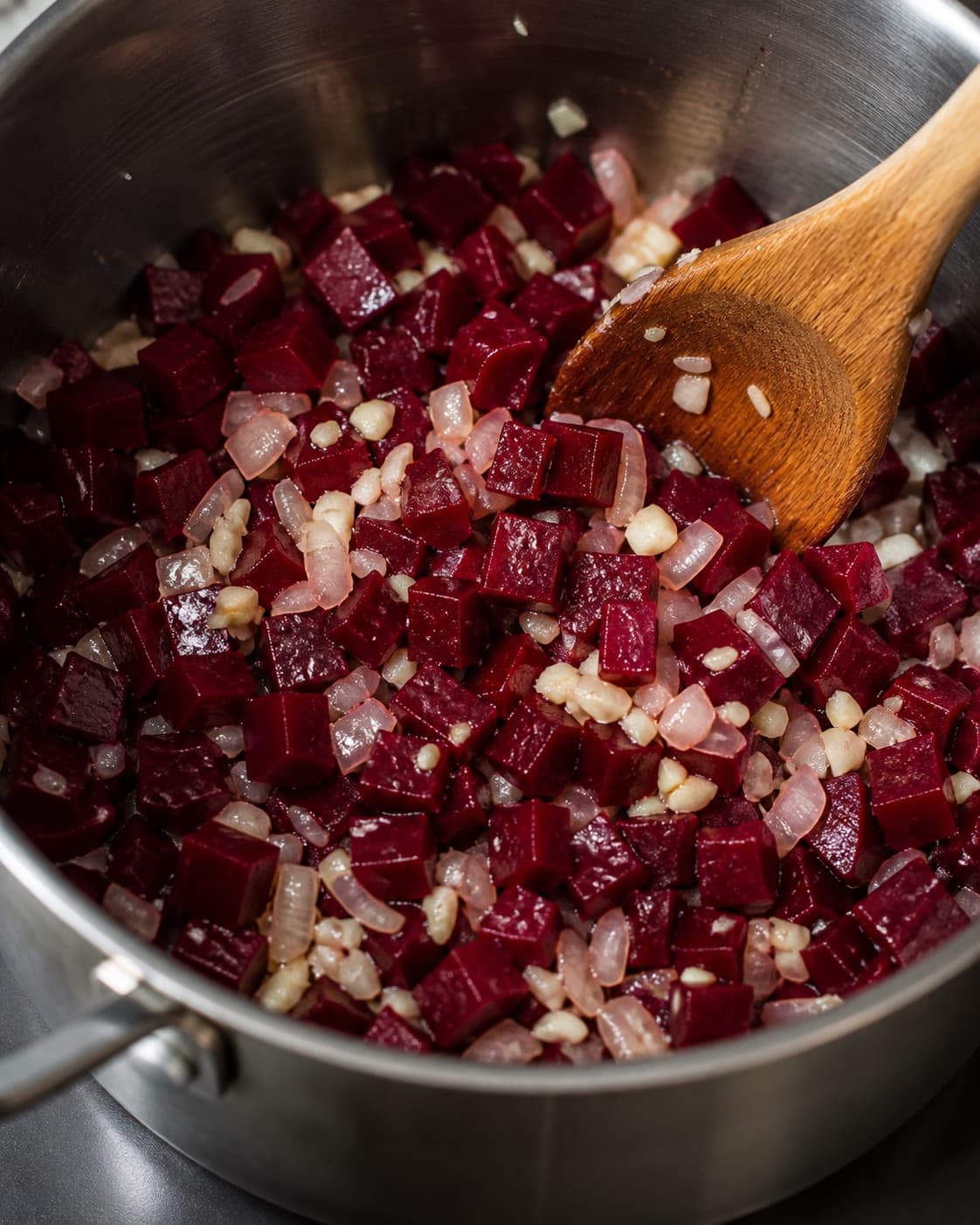 Onion garlic and beetroot sweating glossy in rapeseed oil without browning under tilberedningen af rødbedesuppe