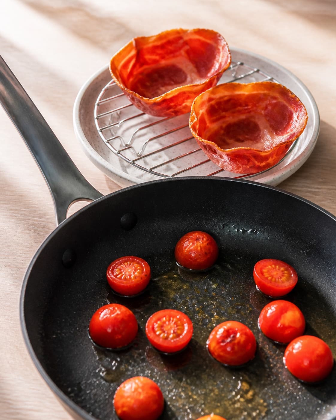 Crisp serrano ham resting while cherry tomatoes blister gently in the pan under tilberedningen af æg med serranoskinke og tomat