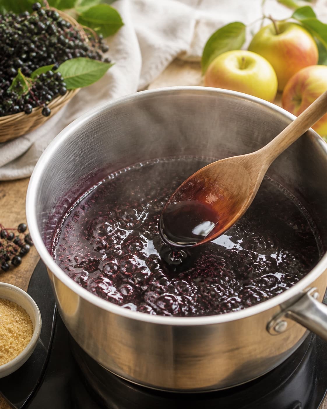 Strained elderberry juice simmering clear and dark as sugar dissolves under tilberedningen af hyldebærsirup
