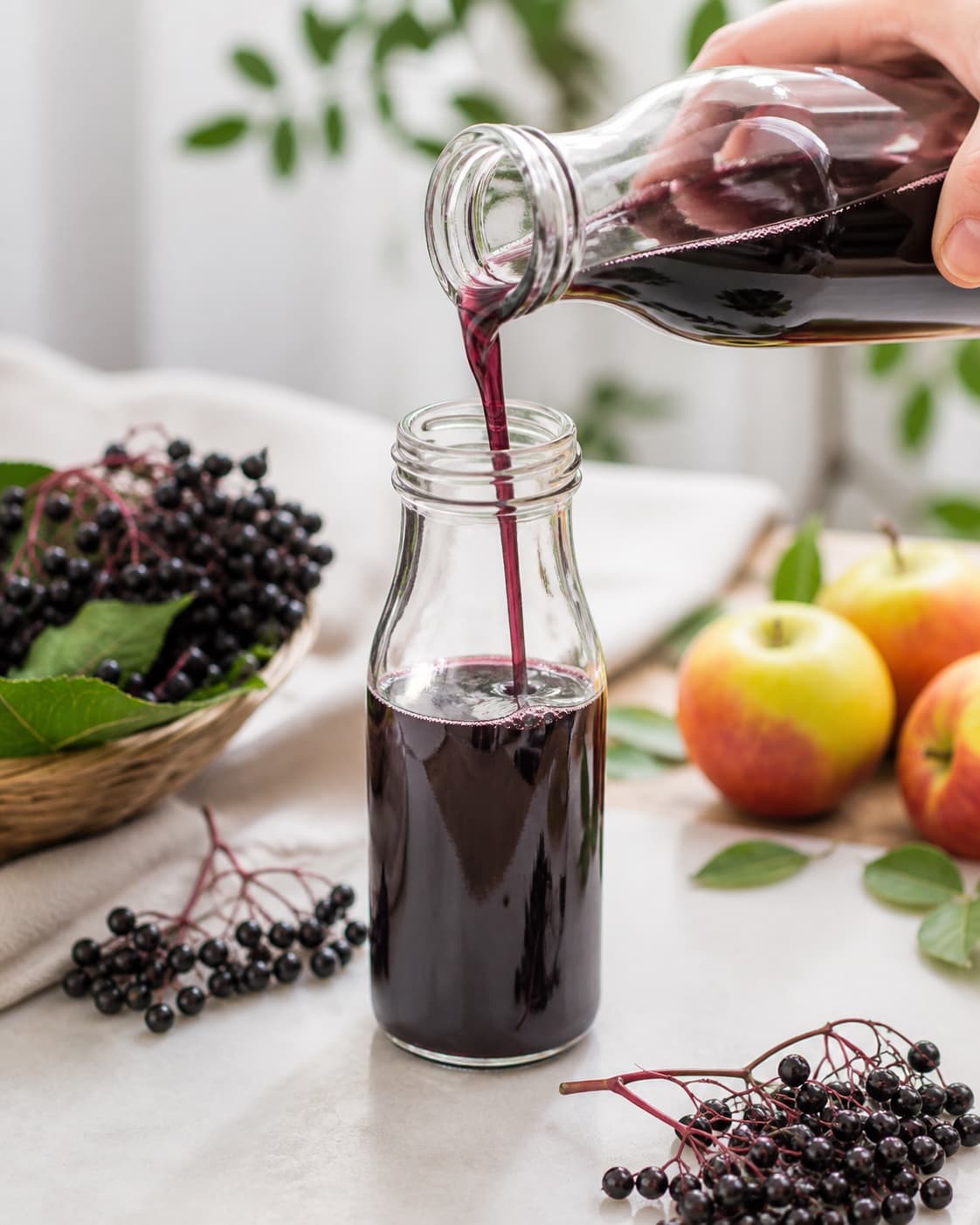 Boiling elderberry syrup being transferred through a funnel into clean hot bottles under tilberedningen af hyldebærsirup