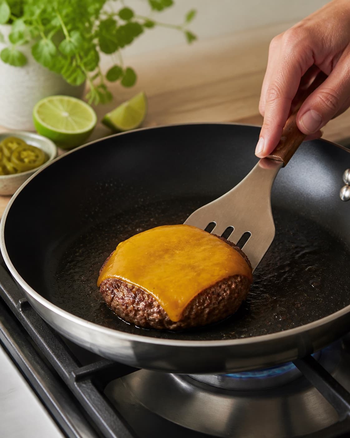 Beef burger patties searing to 75 degrees as cheddar melts under a lid under tilberedningen af mexicansk burger med guacamole