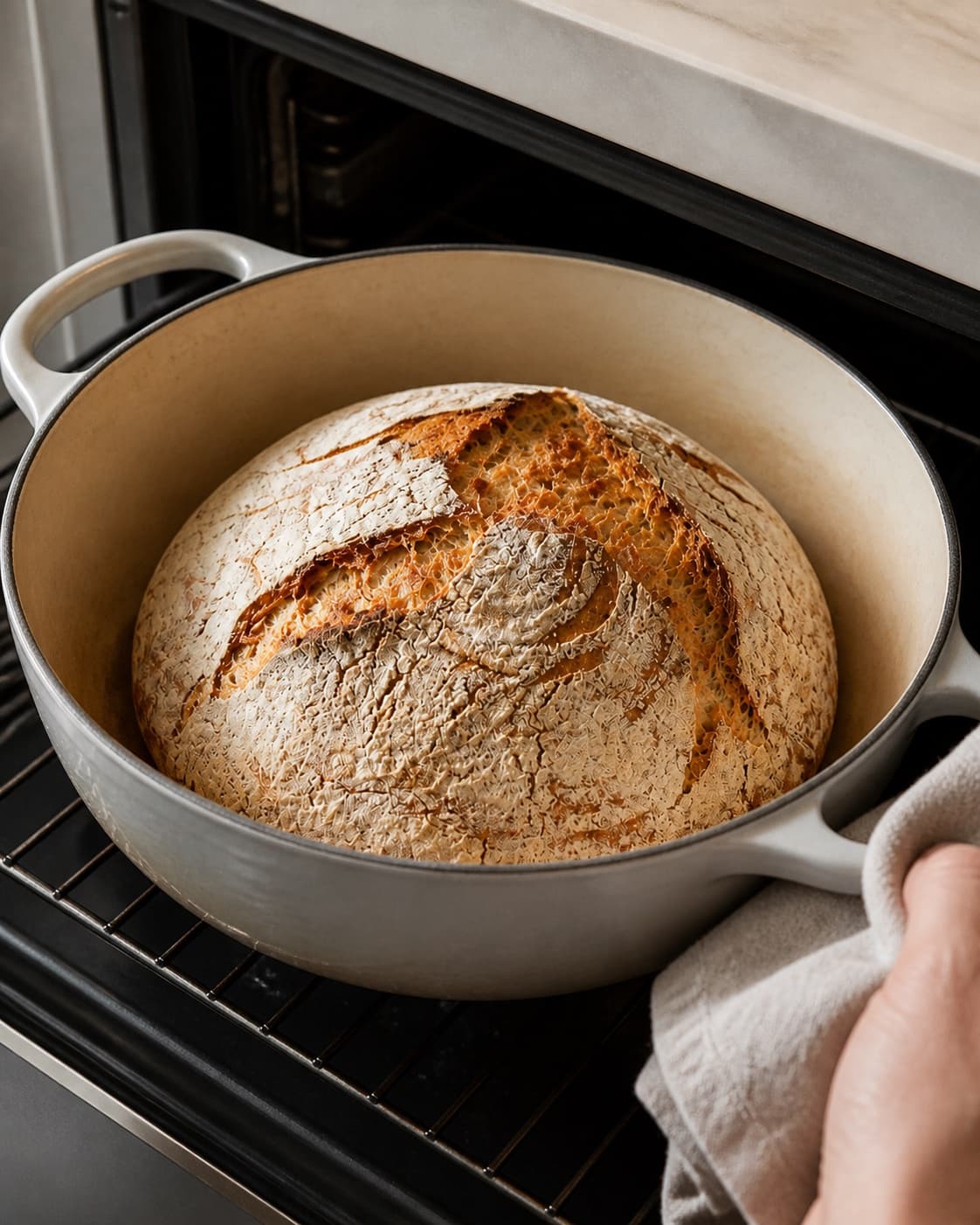 A single Dutch oven loaf baking with a bold score and deep golden crust under tilberedningen af grydebrød