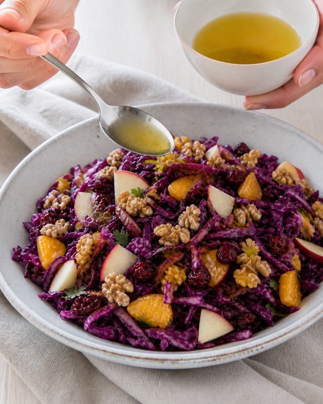 Winter red cabbage salad finished with freshly toasted walnuts and a final spoonful of dressing under tilberedningen af vintersalat med rødkål og æbler