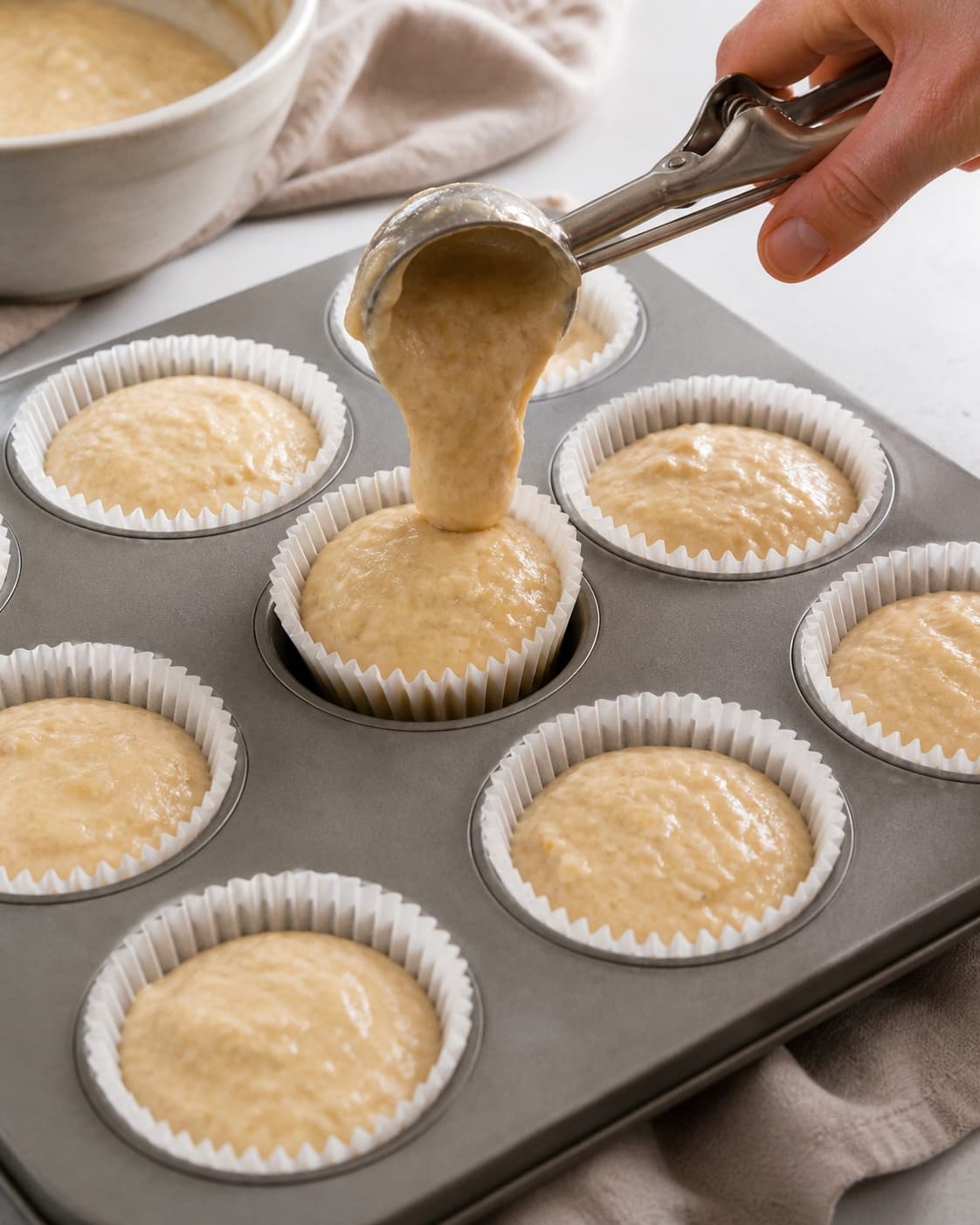 Equal portions of banana muffin batter filling paper cases to the same height under tilberedningen af bananmuffins