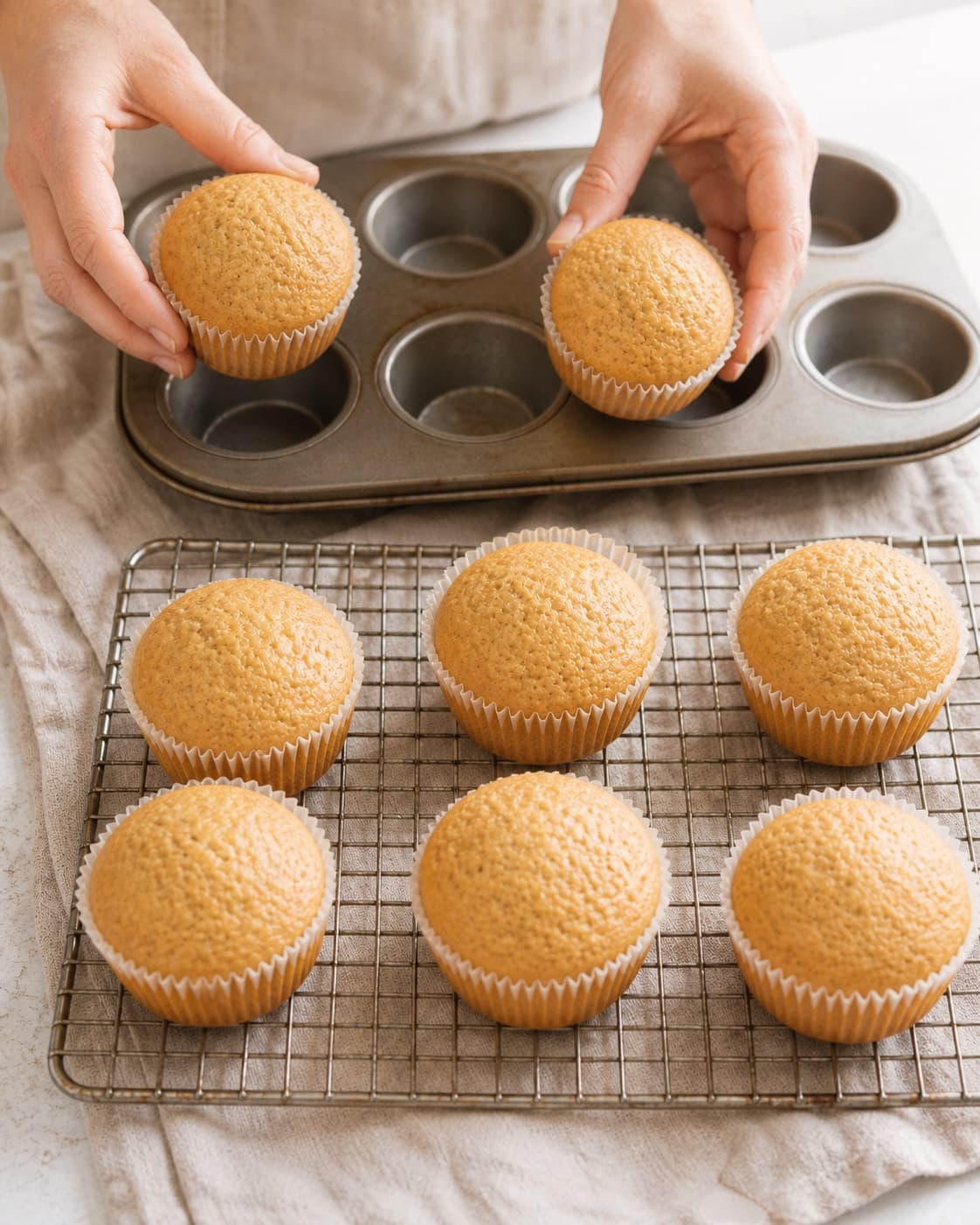Fresh banana muffins cooling on a wire rack after a brief rest in their baking tray under tilberedningen af bananmuffins