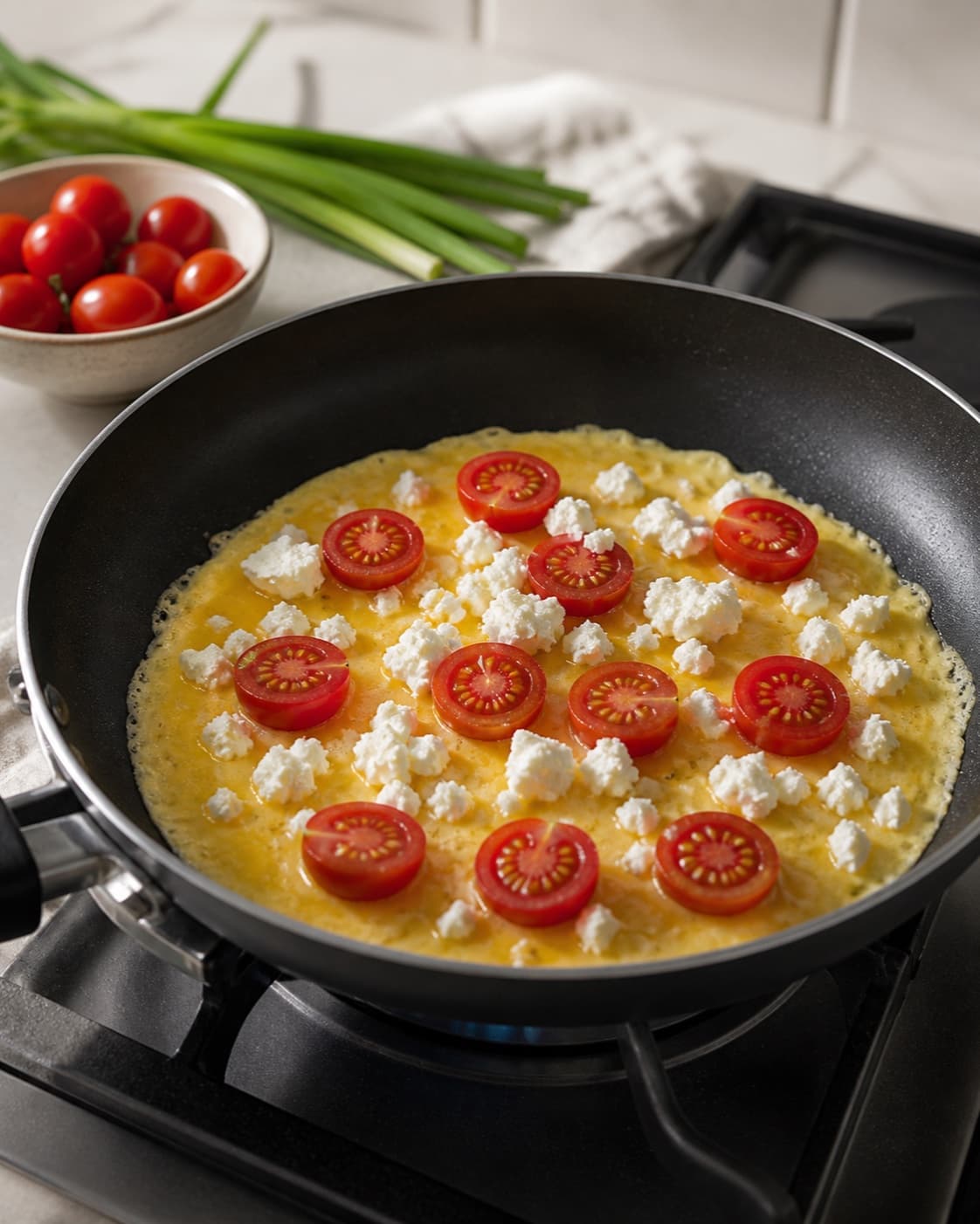 Egg mixture poured around dry sauteed tomatoes spinach spring onions and feta in a buttered pan under tilberedningen af omelet med feta og tomat