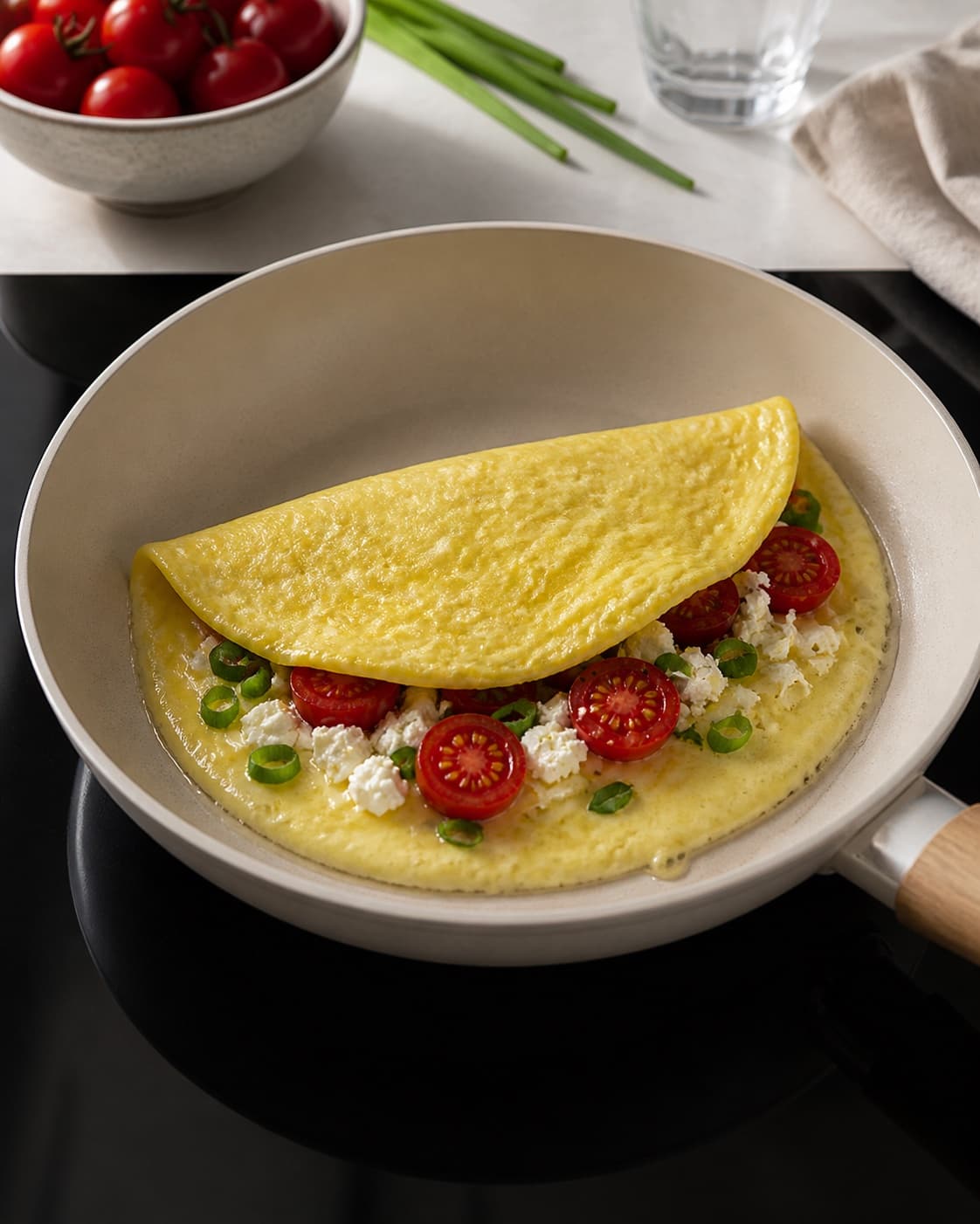 Tender omelette setting gently around tomato spinach feta and spring onion filling under tilberedningen af omelet med feta og tomat