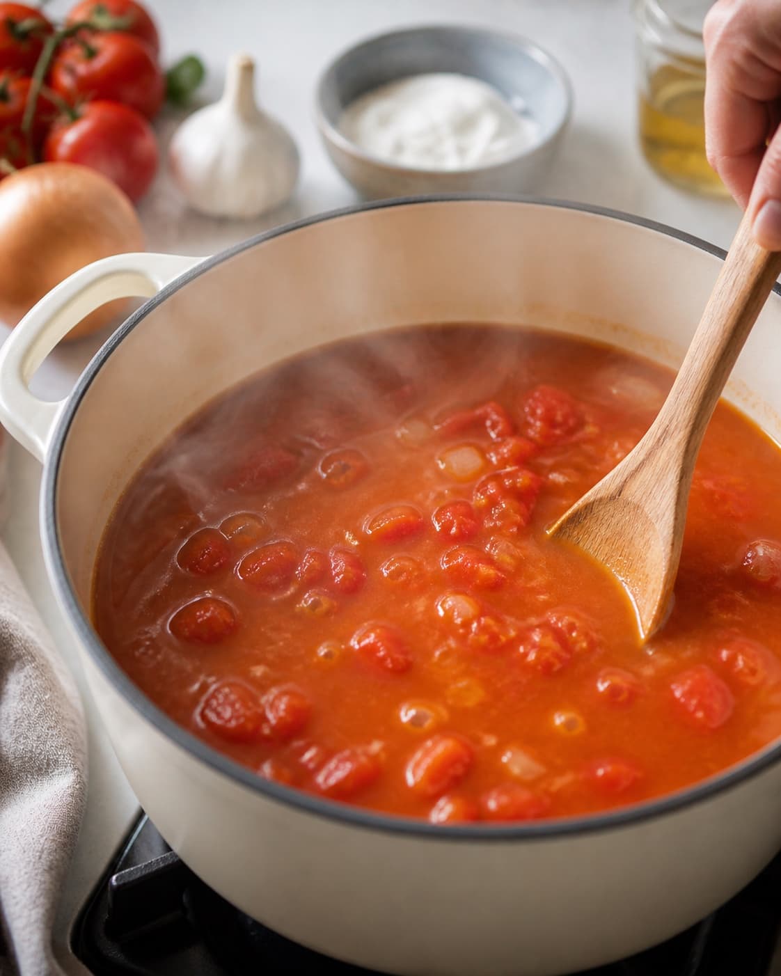 Fresh tomatoes and vegetable stock simmering gently over the concentrated tomato base under tilberedningen af cremet tomatsuppe med mascarpone