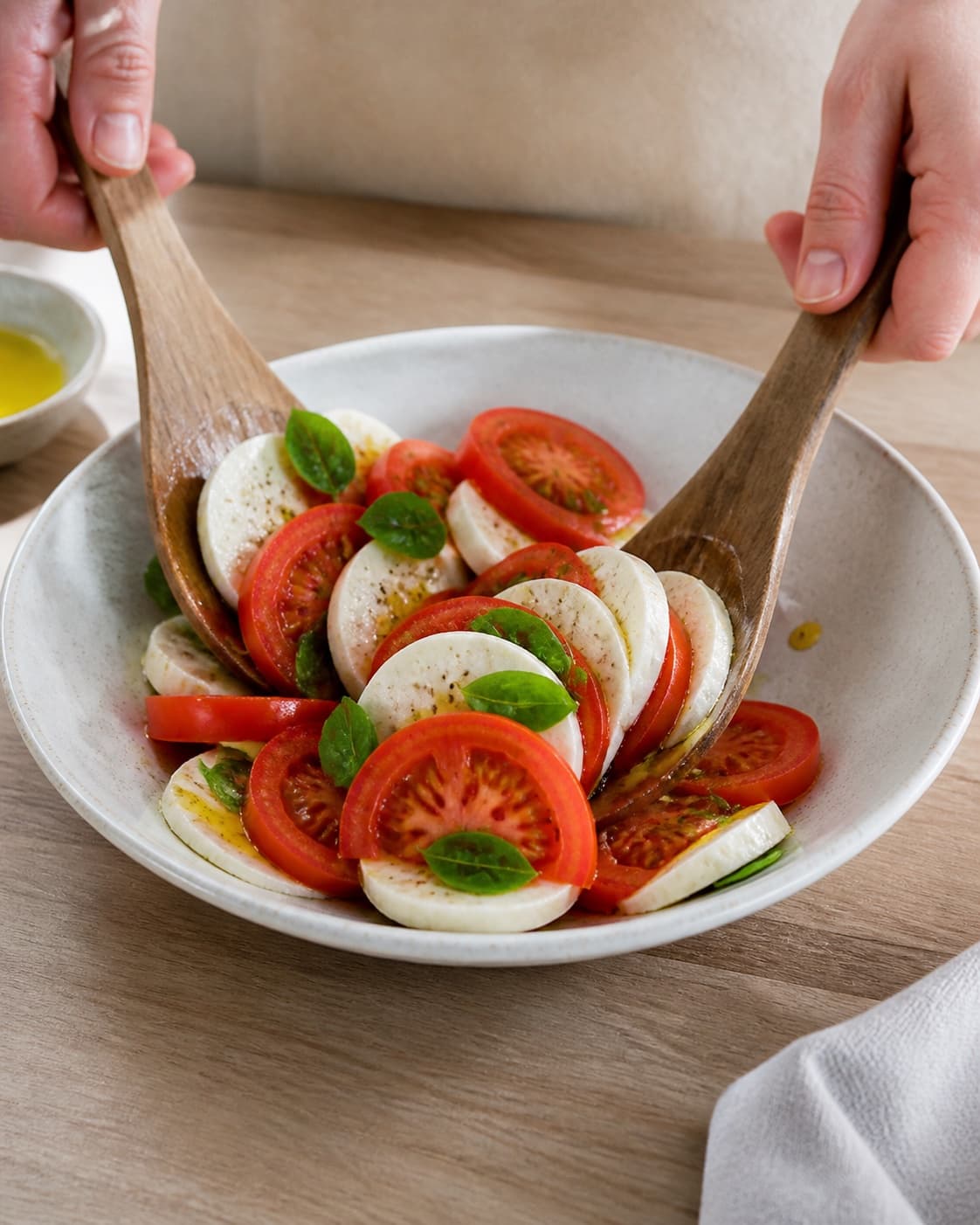 Tomato slices and torn mozzarella arranged loosely in alternating overlapping layers under tilberedningen af tomatsalat med mozzarella