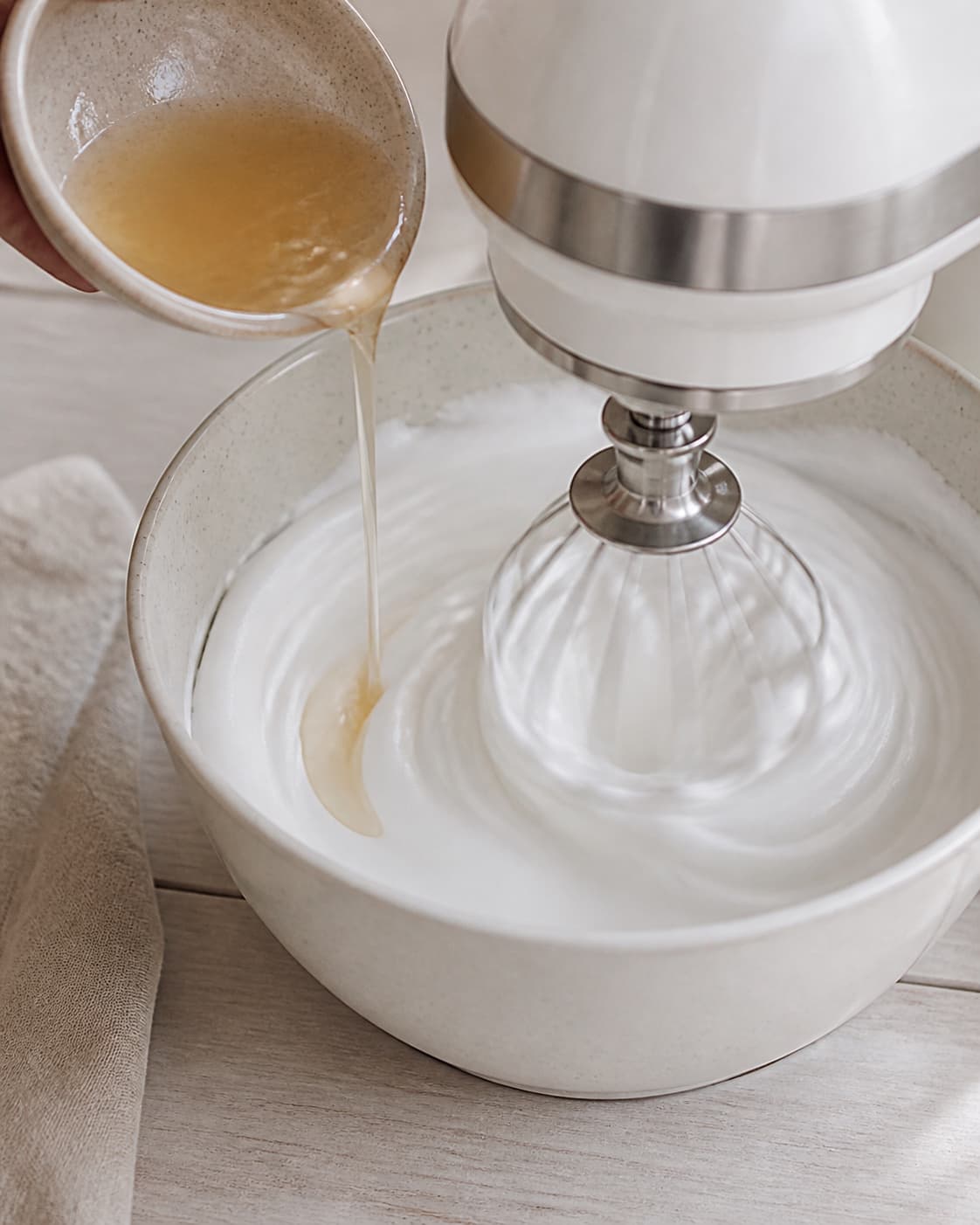 Hot syrup streamed into softly whipped egg whites while the mixer builds glossy Italian meringue under tilberedningen af hjemmelavet guf til is