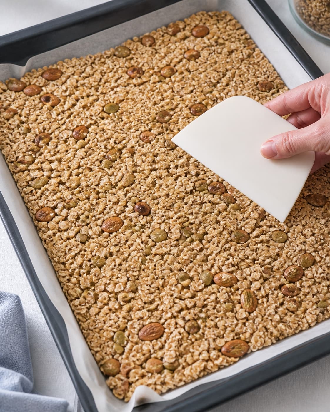 Coated muesli spread in one even layer and lightly pressed on parchment before baking under tilberedningen af müsli