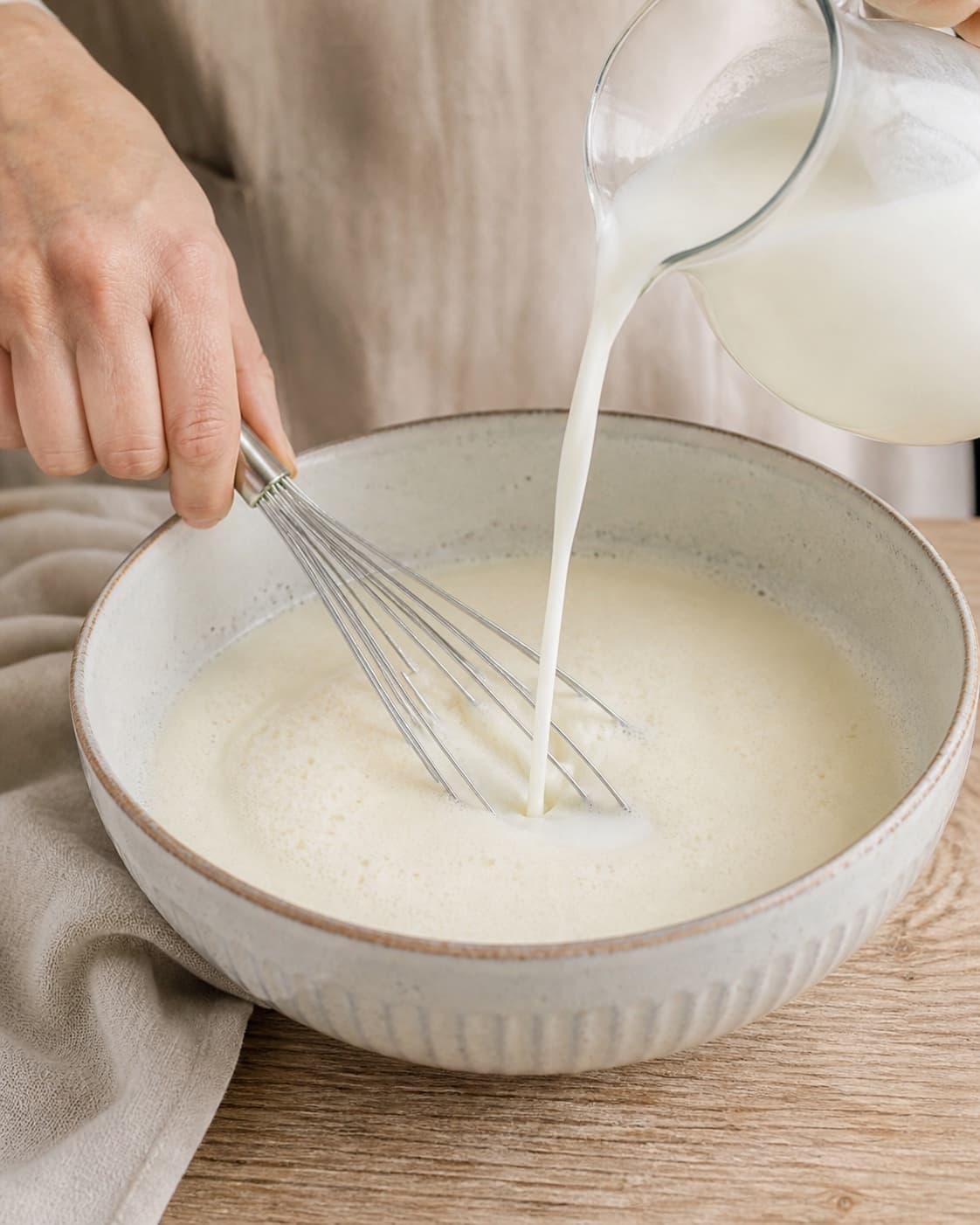 Cold buttermilk poured gradually into airy vanilla cultured milk base under tilberedningen af koldskål