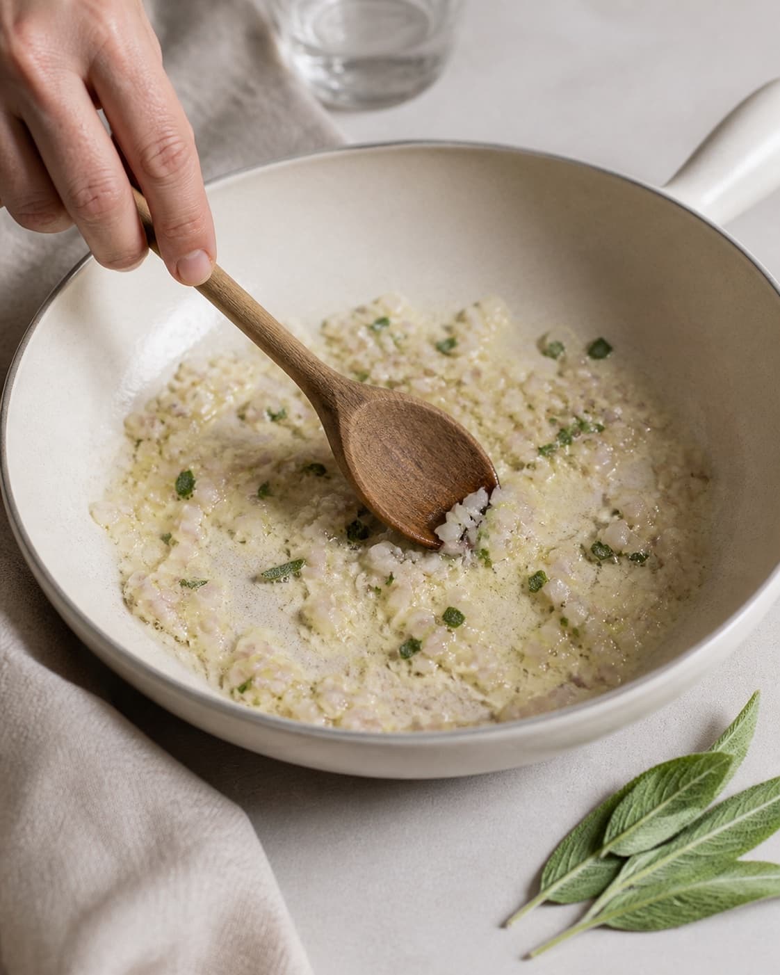 Finely chopped shallot and fresh sage softening gently in butter without browning under tilberedningen af ravioli med gorgonzolasauce