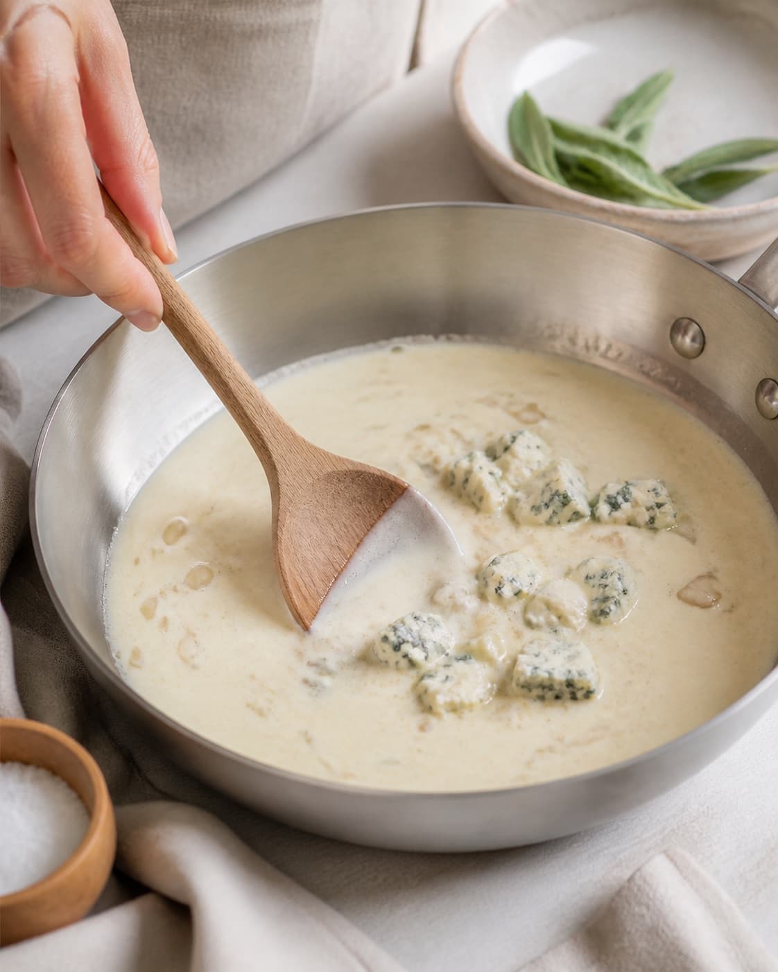 Gorgonzola being melted gradually into warm cream and soft shallot under tilberedningen af ravioli med gorgonzolasauce
