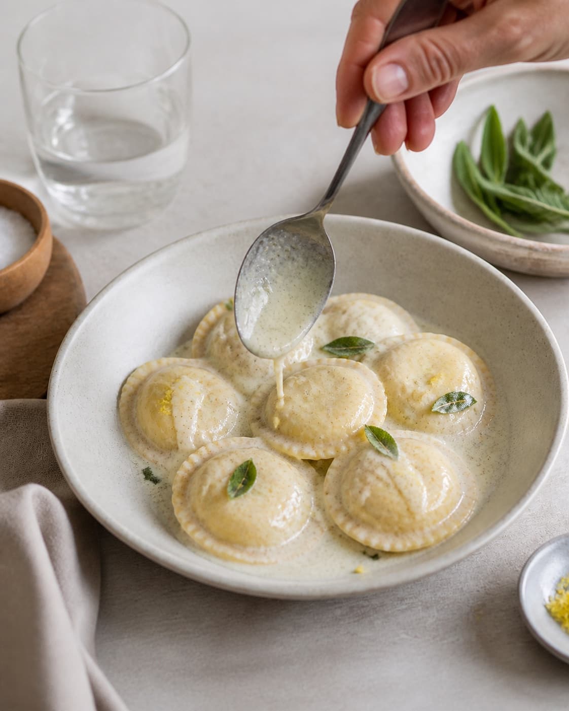 Intact cooked ravioli being gently coated in glossy gorgonzola sauce with sage and lemon zest under tilberedningen af ravioli med gorgonzolasauce