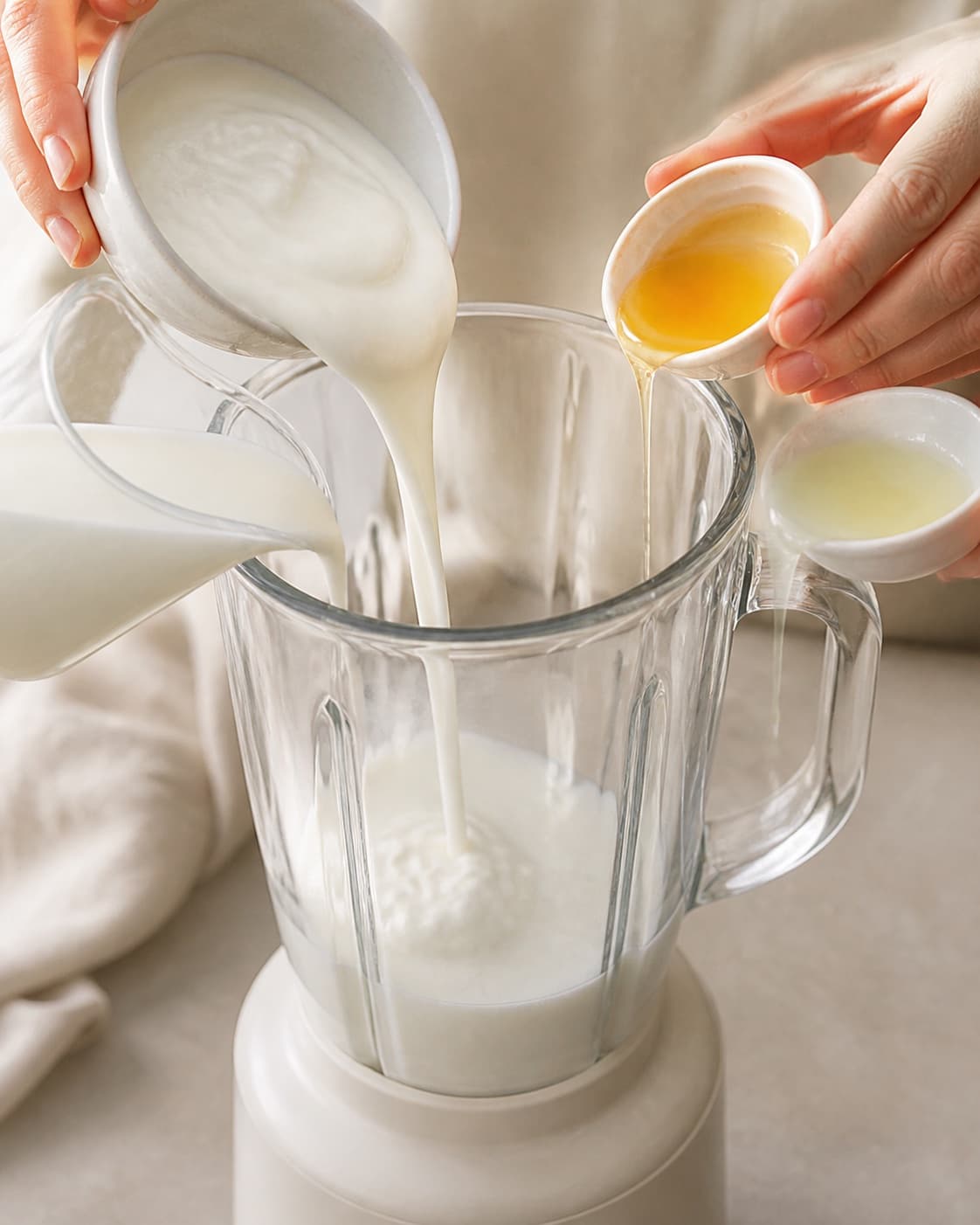 Milk skyr lime juice and honey being poured into the blender before fruit under tilberedningen af hindbærsmoothie med vanilje