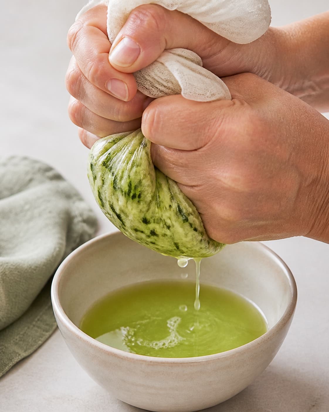 Grated zucchini being squeezed firmly in a clean cloth after salting under tilberedningen af kyllingefrikadeller med squash