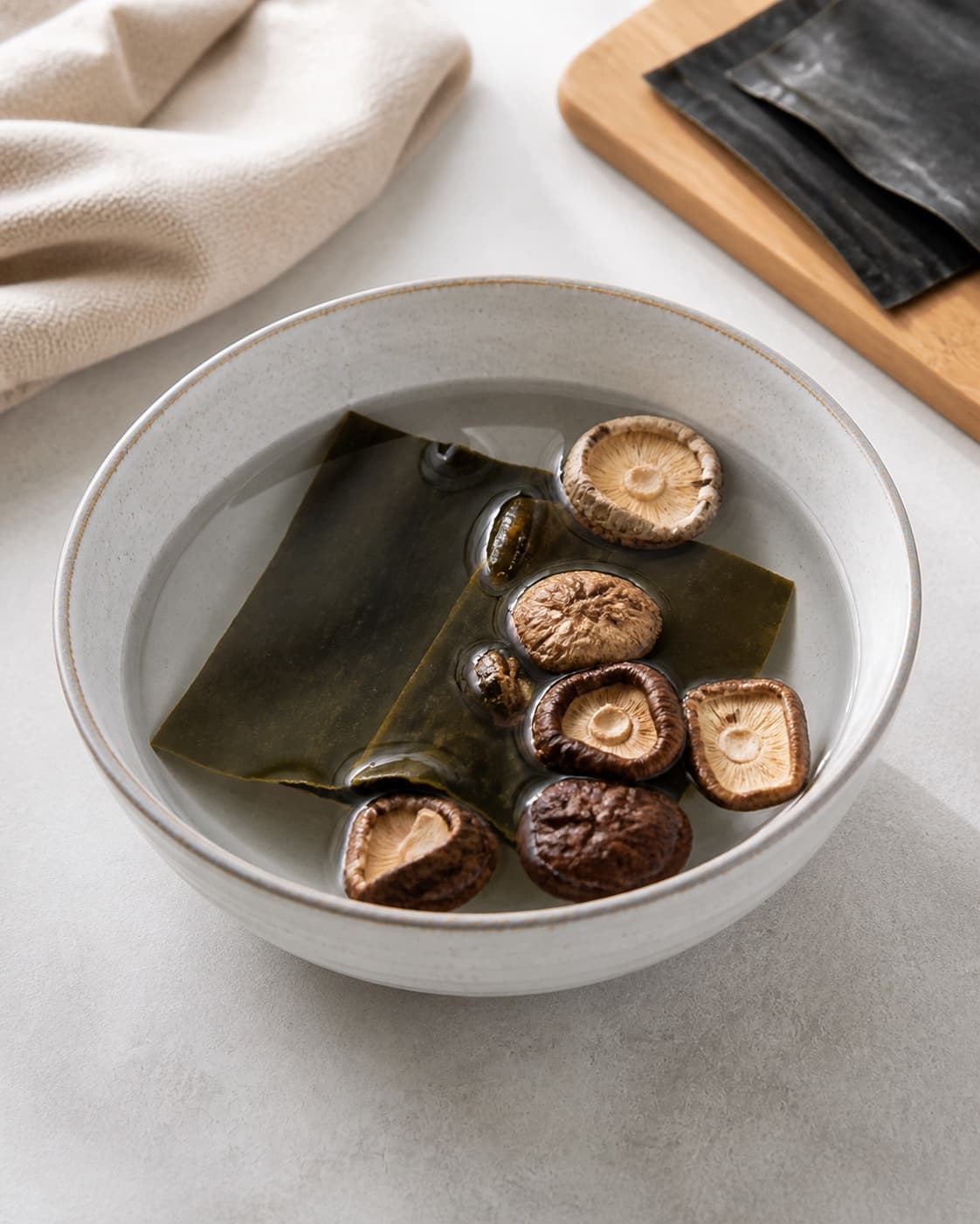 Dried kombu and shiitake soaking in cold water to make a clear plant dashi under tilberedningen af misosuppe med tofu og wakame