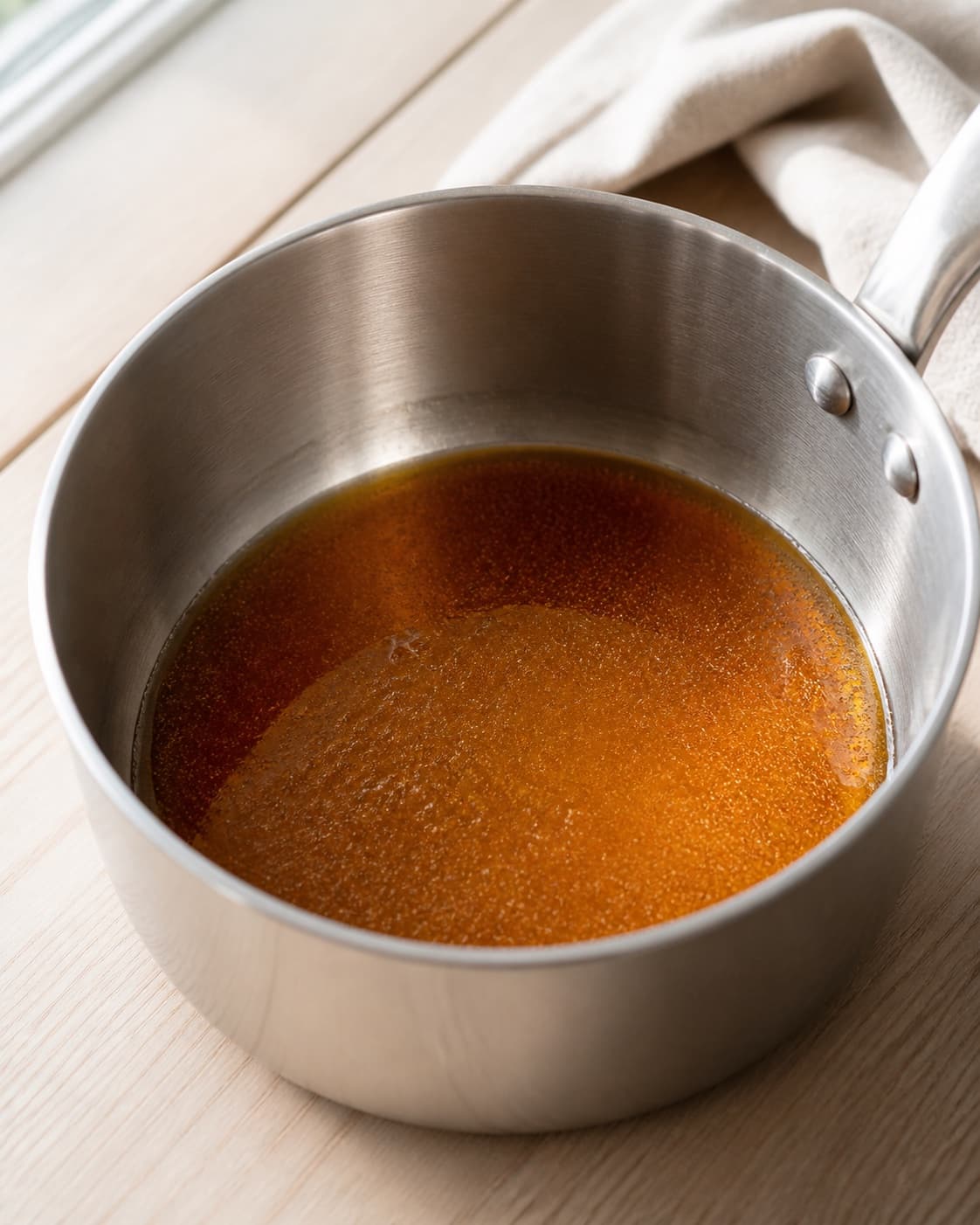 Sugar and glucose melting into a clear even amber caramel in a clean heavy saucepan under tilberedningen af saltkarameller - flødekarameller