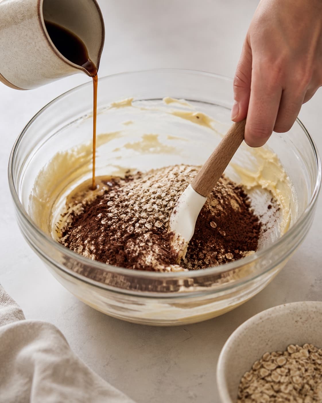 Cocoa and oats being folded into creamed butter while cooled coffee is added little by little under tilberedningen af havregrynskugler
