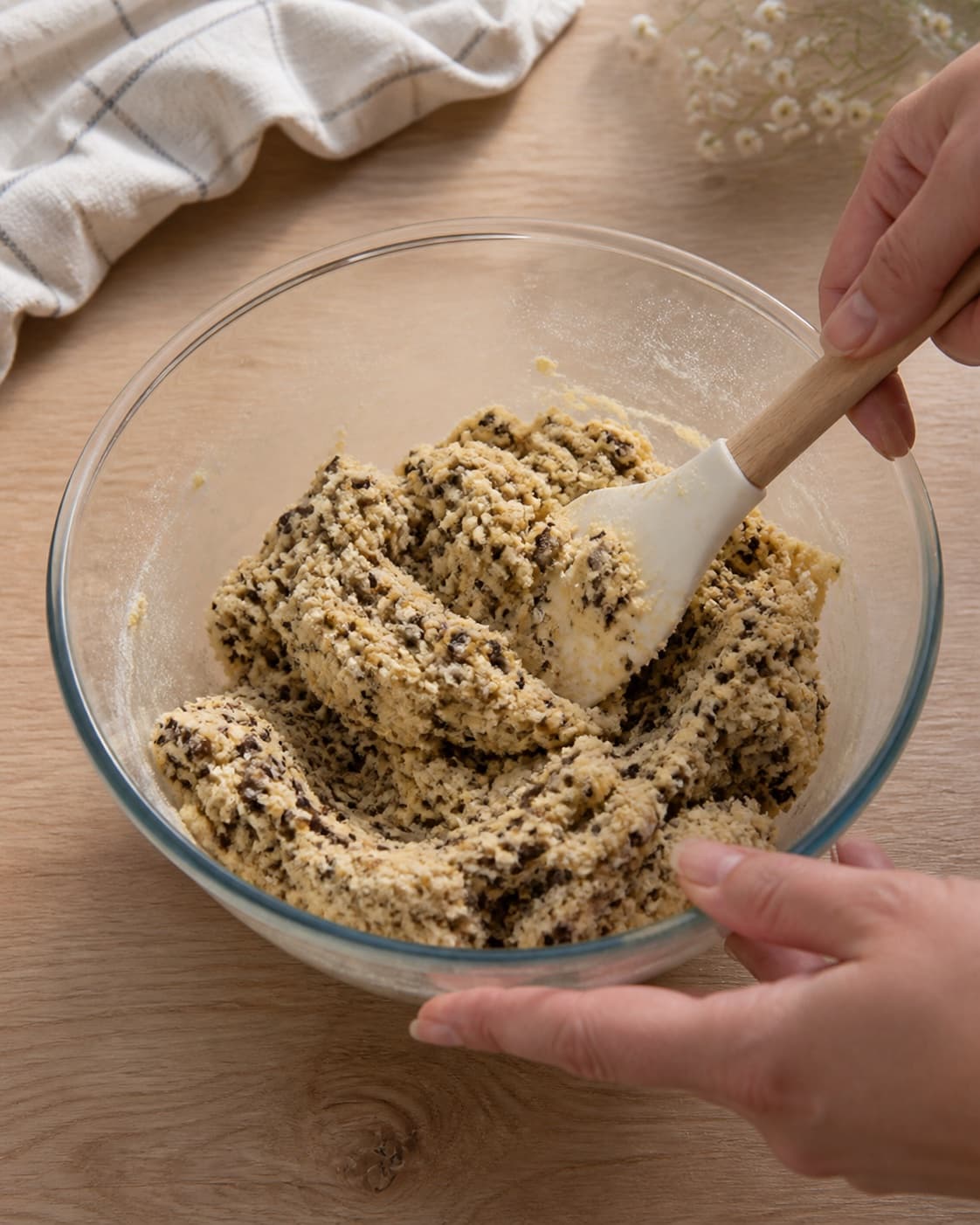 Finely chopped dark chocolate being folded evenly into pale cookie dough with only a few strokes under tilberedningen af specier med chokolade