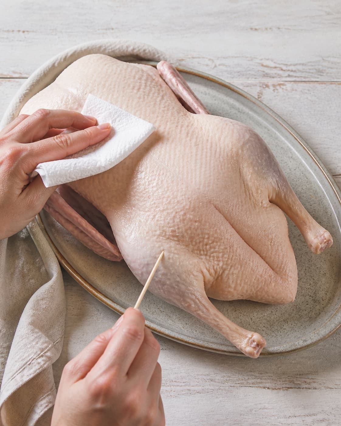 One whole raw duck being thoroughly patted dry and its fatty thigh skin lightly pricked, no stuffing and no cooked skin under tilberedningen af andesteg langtidsstegt