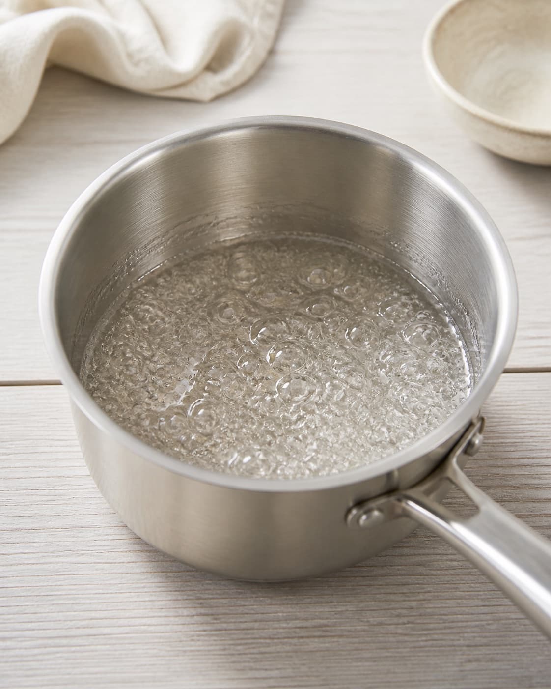 Clear sugar water and glucose syrup dissolving in a spotless saucepan with small even bubbles, no colour, butter or nuts under tilberedningen af karamelbrud