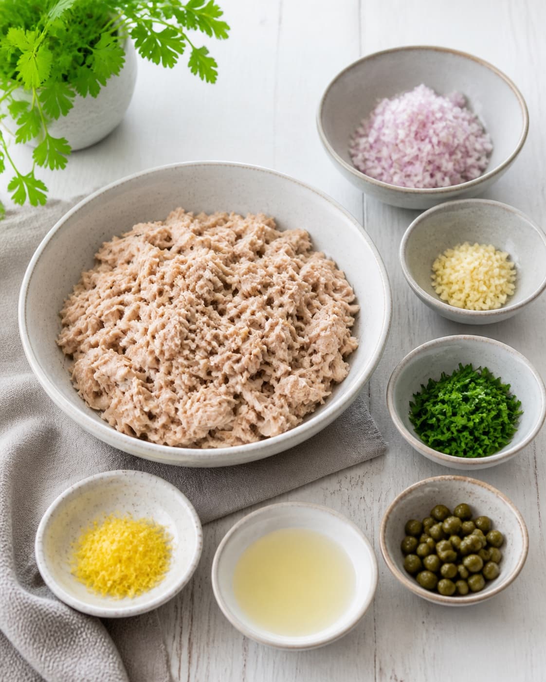 Drained tuna flakes, finely chopped shallot garlic and parsley, lemon zest juice and capers prepared separately, no pasta or sauce under tilberedningen af pasta med tunsauce