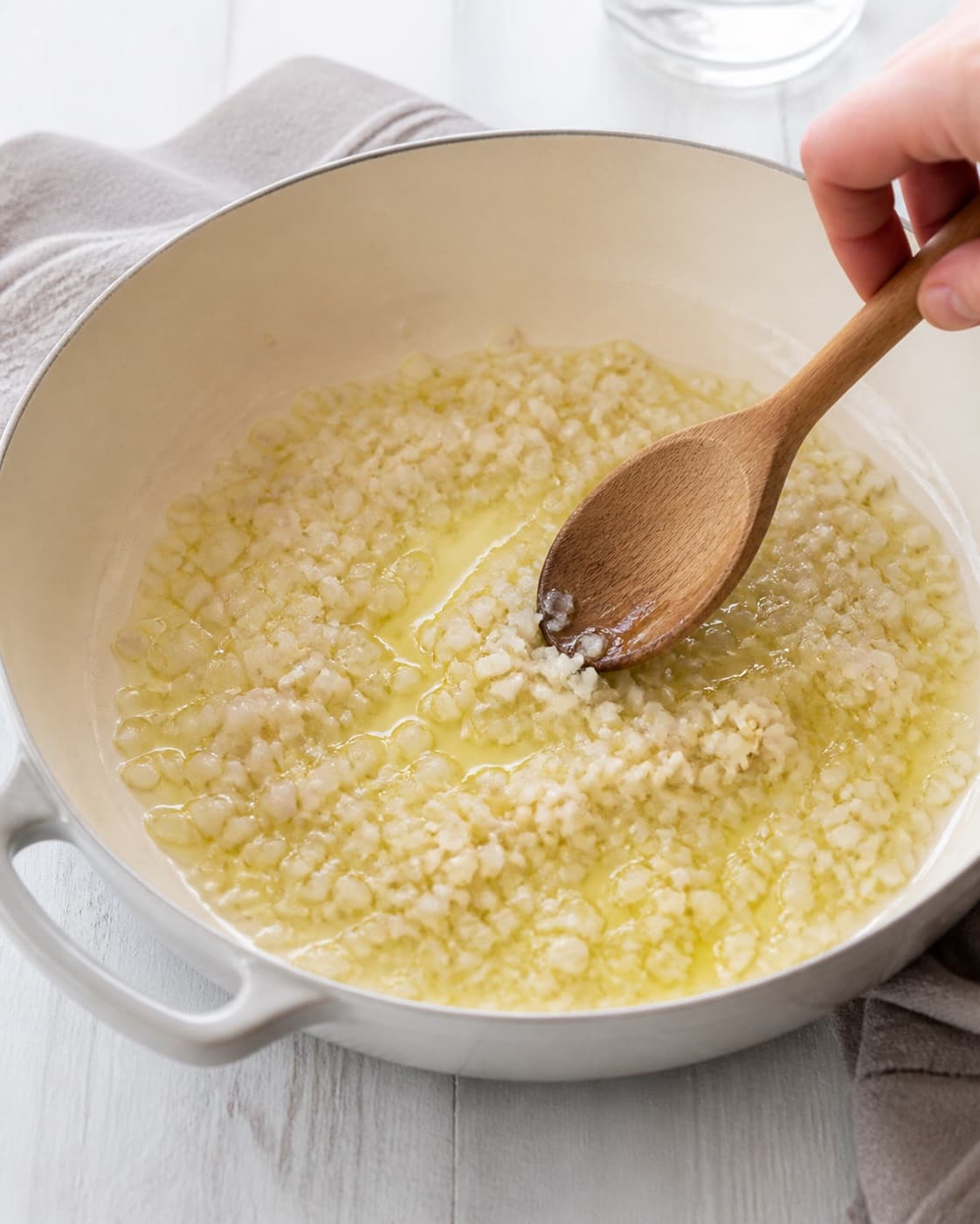 Finely chopped shallot softening in olive oil with garlic just added, translucent and pale, no tuna cream or pasta under tilberedningen af pasta med tunsauce
