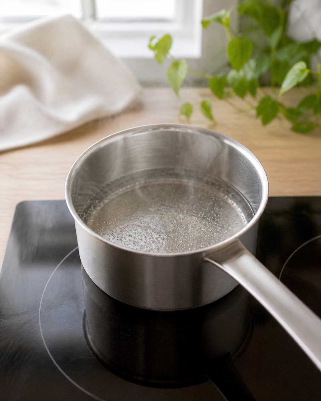 Clear sugar syrup gently simmering in one small saucepan with every crystal dissolved, no lavender lemon or bottle under tilberedningen af lavendelsirup