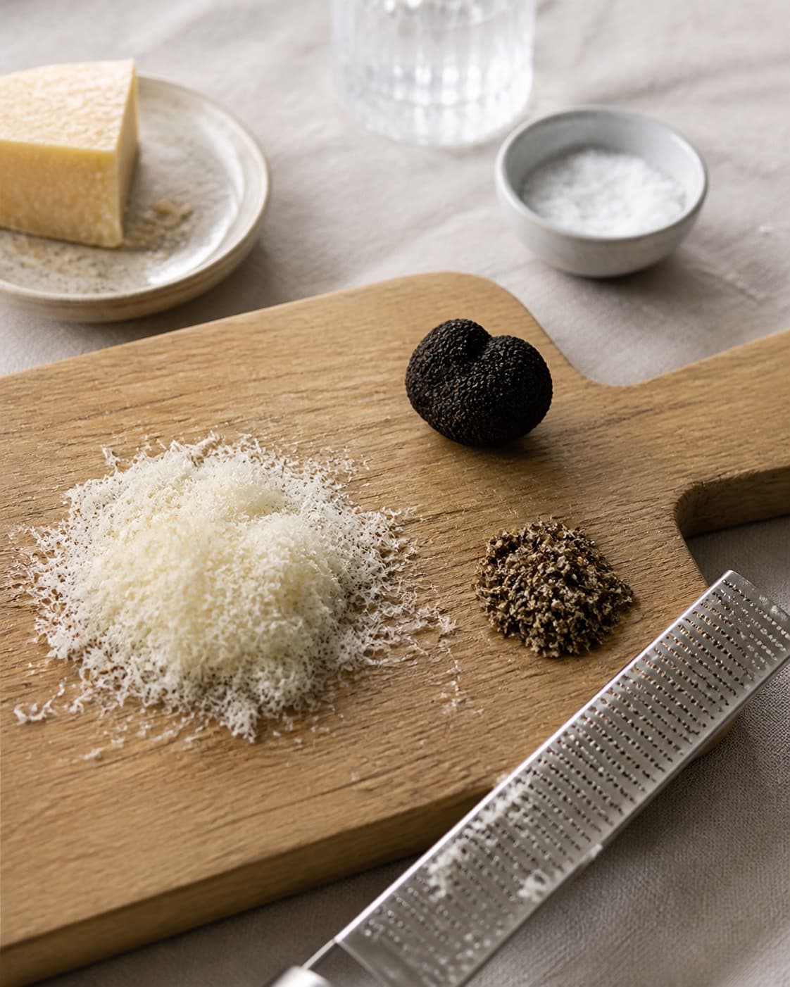 One clean dry black truffle beside finely grated parmesan and a small separate pile of minced truffle, no pasta butter or sauce under tilberedningen af pasta med trøffel