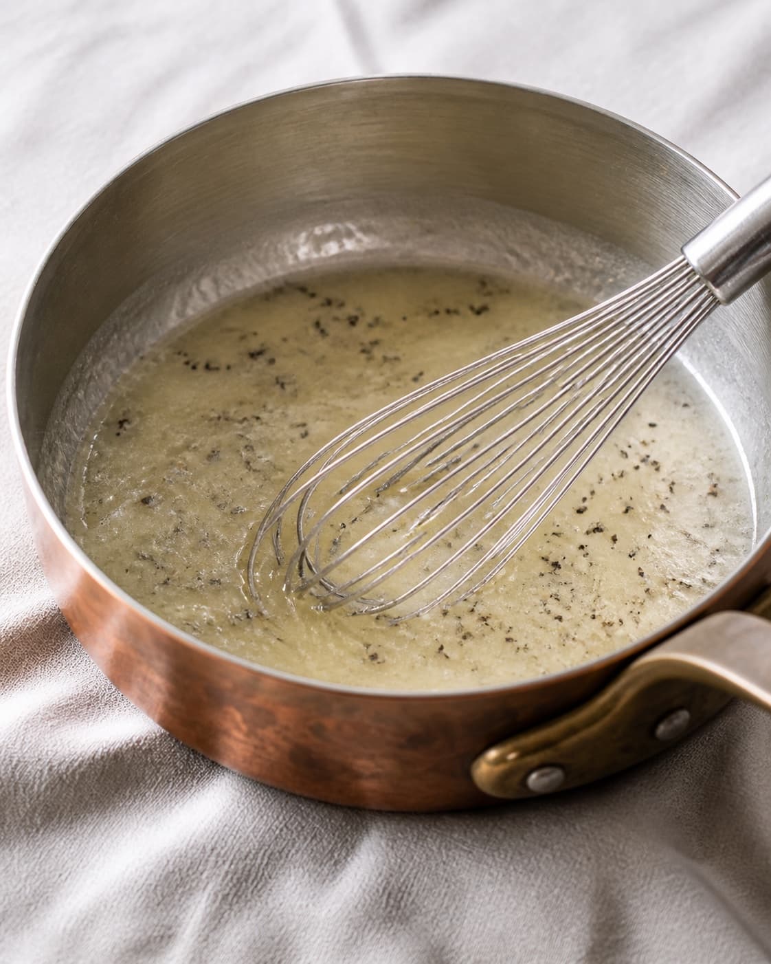 Pale glossy butter and pasta-water emulsion with fine black truffle pieces in one pan, no pasta parmesan or browned butter under tilberedningen af pasta med trøffel