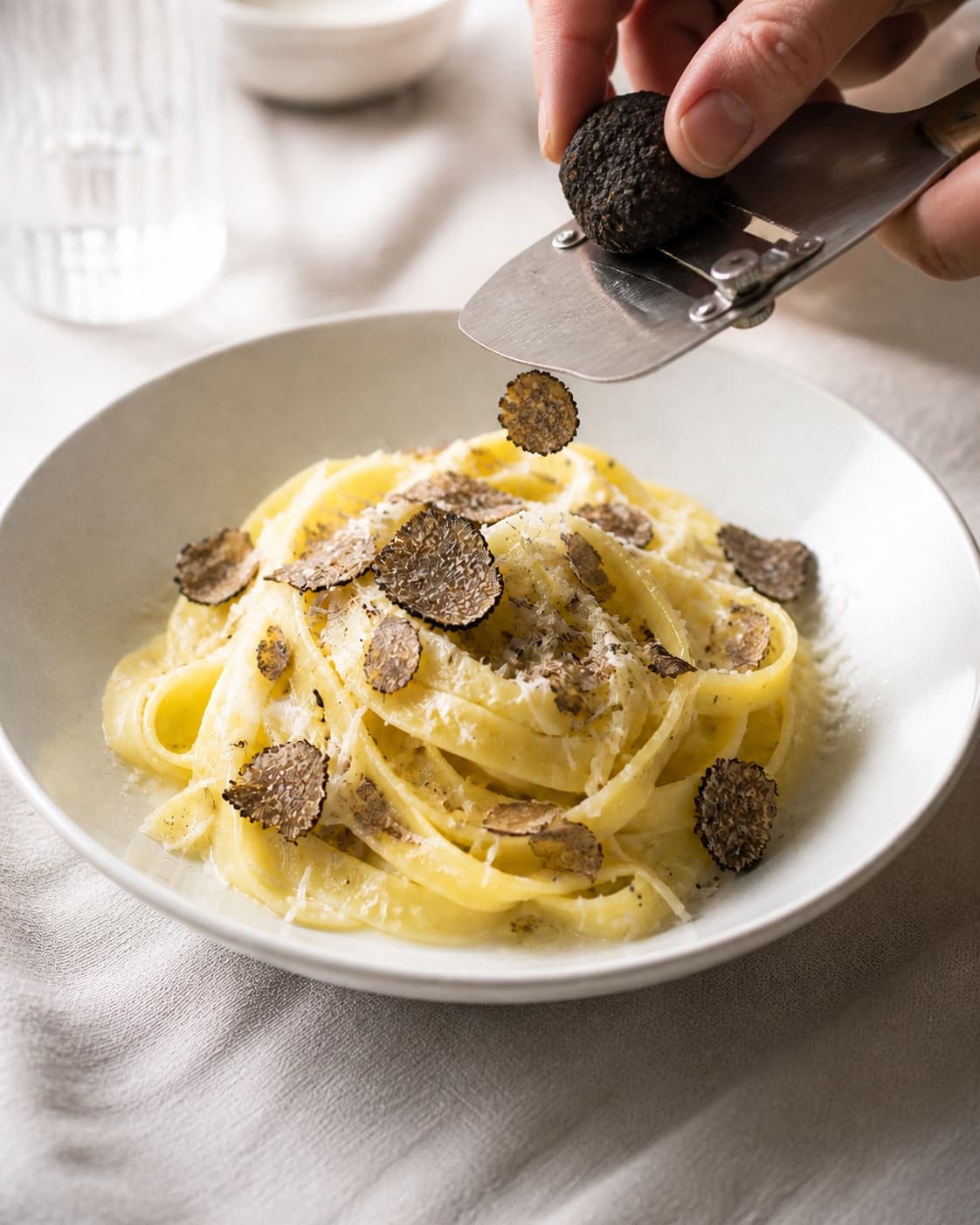 One warm plate of glossy tagliatelle topped with paper-thin black truffle slices and fine parmesan, no herbs cream pool or extra dishes under tilberedningen af pasta med trøffel
