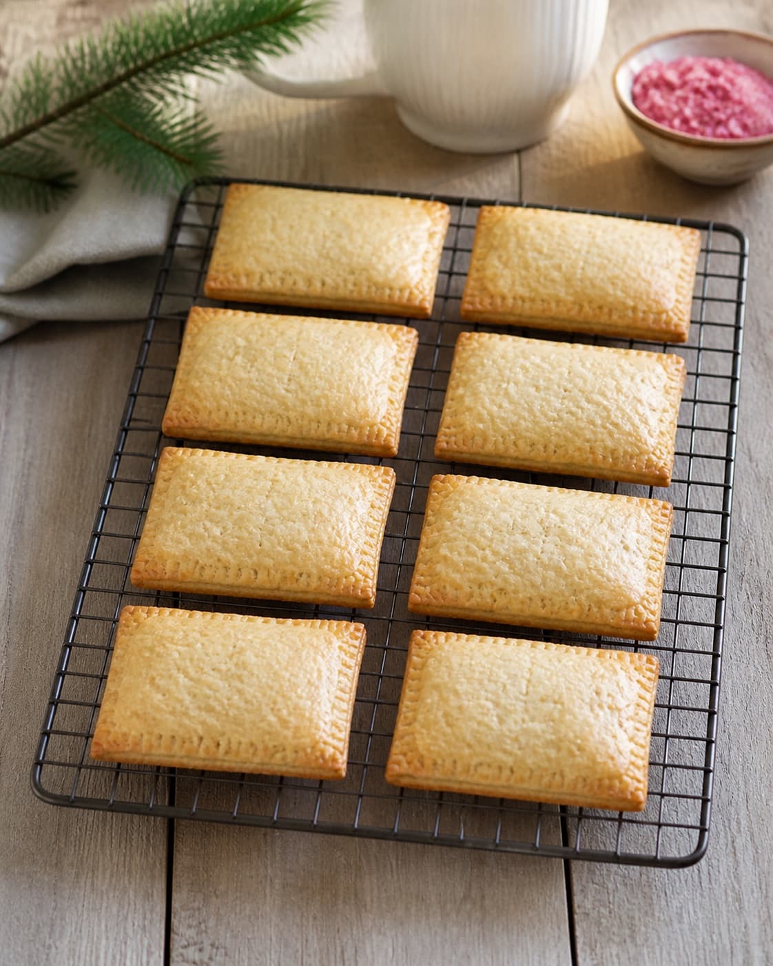 Exactly eight evenly golden baked rectangular pop tarts cooling on one rack, no glaze candy jam leaks or extra pastries under tilberedningen af jule-poptarts