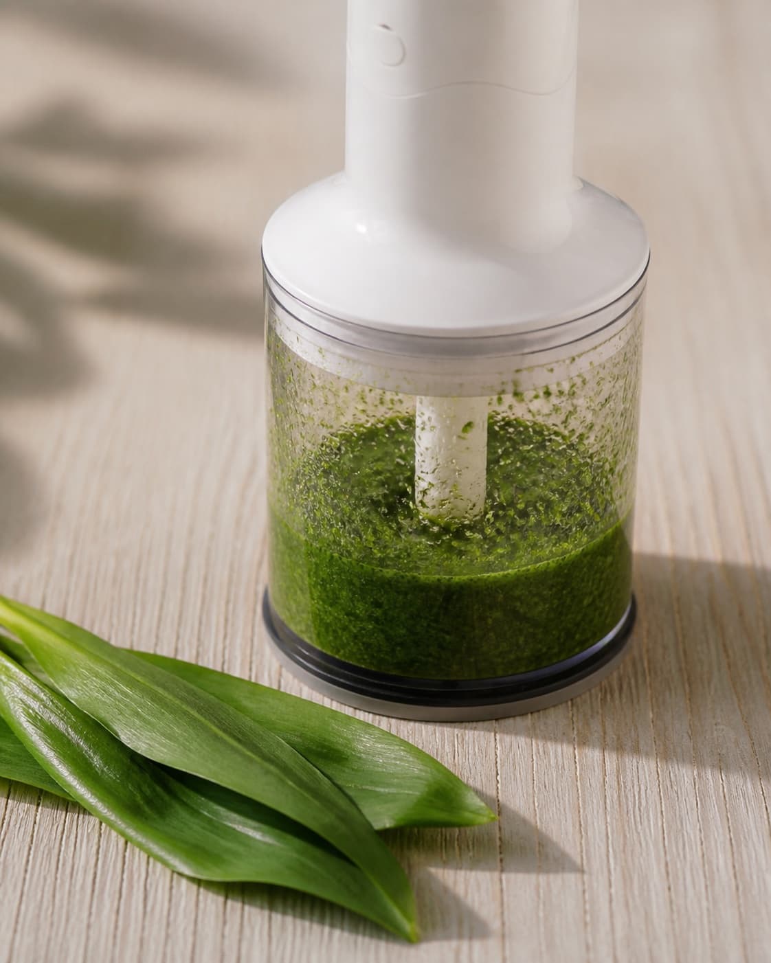 One mini processor holding vivid green wild-garlic oil with fine leaf flecks, no asparagus roe cream dill or plated food under tilberedningen af asparges med ramsløg og stenbiderrogn