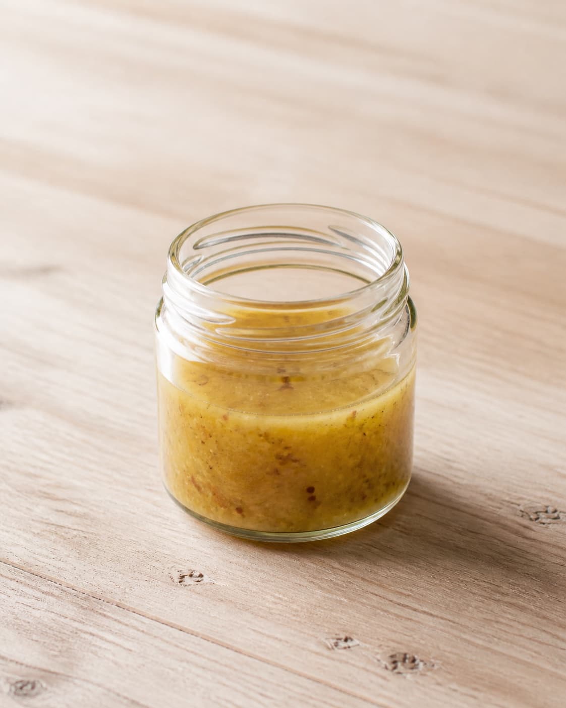 One small open glass jar holding emulsified golden mustard vinaigrette, no cabbage fennel onion chorizo pomegranate or serving bowl under tilberedningen af spidskålssalat med chorizo og granatæble