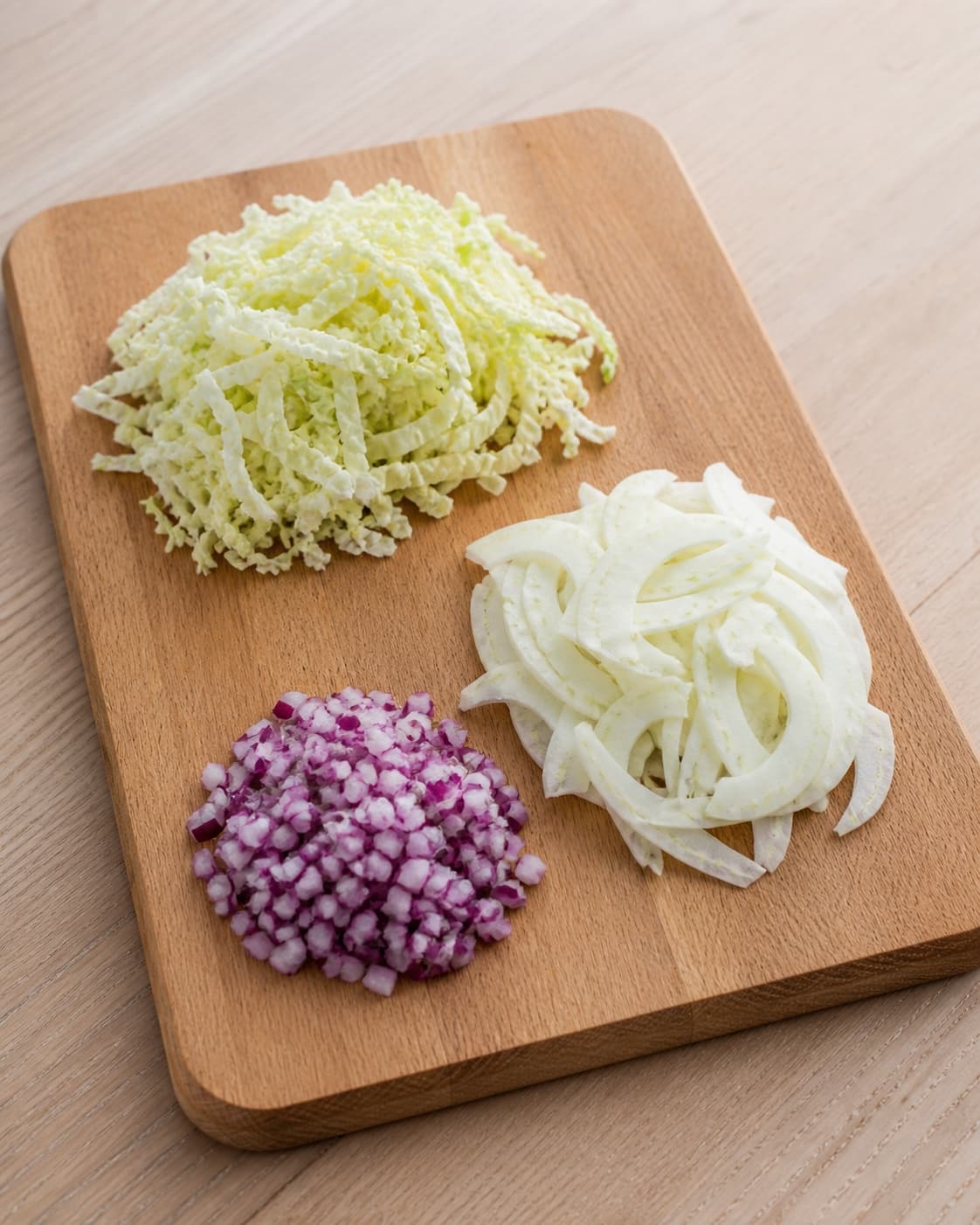 Three clearly separate piles of paper-thin green pointed cabbage, pale fennel and finely diced purple red onion on one board, no dressing chorizo pomegranate or cress under tilberedningen af spidskålssalat med chorizo og granatæble